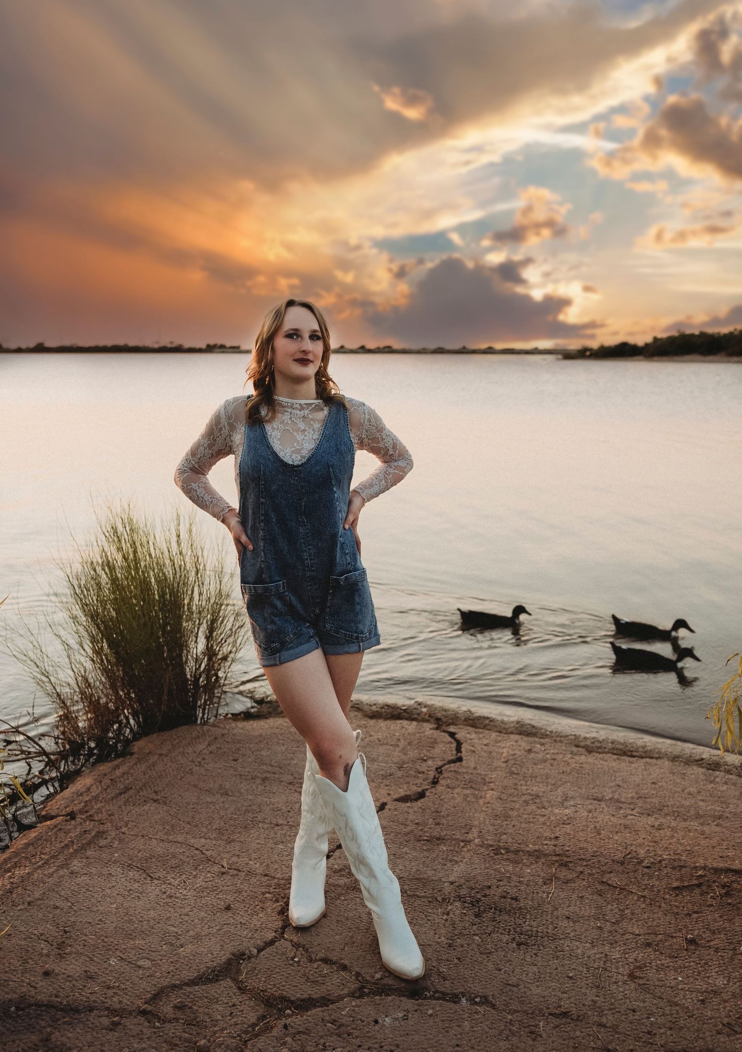 Class of 2027 senior posing by the lake beneath a colorful sunset sky during a cinematic senior portrait session in Abilene, Texas.