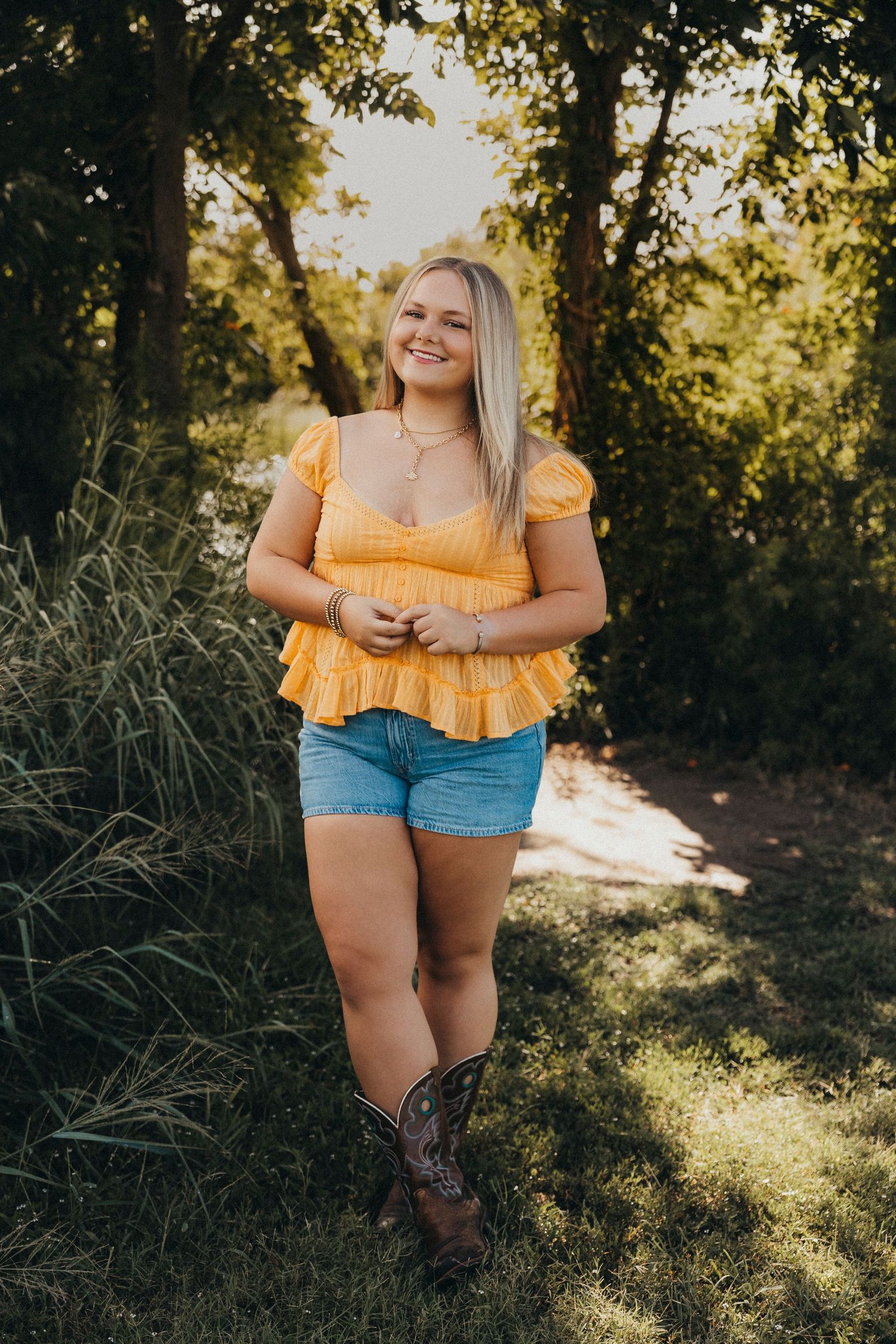 Outdoor senior photos of a Class of 2027 senior in a yellow top and cowboy boots during a golden hour senior portrait session in Abilene, Tx