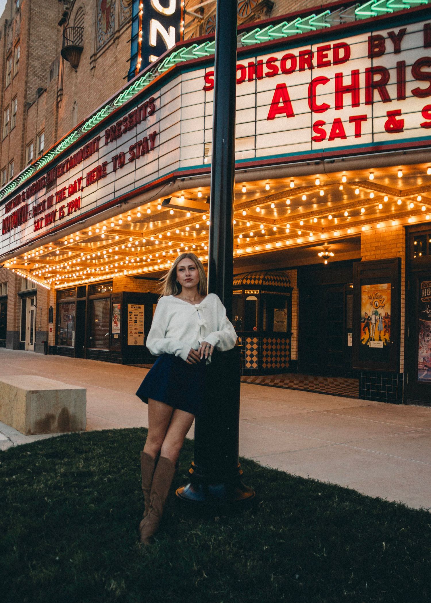 Downtown senior portrait session in Abilene TX featuring a high school senior posing near a theater at sunset