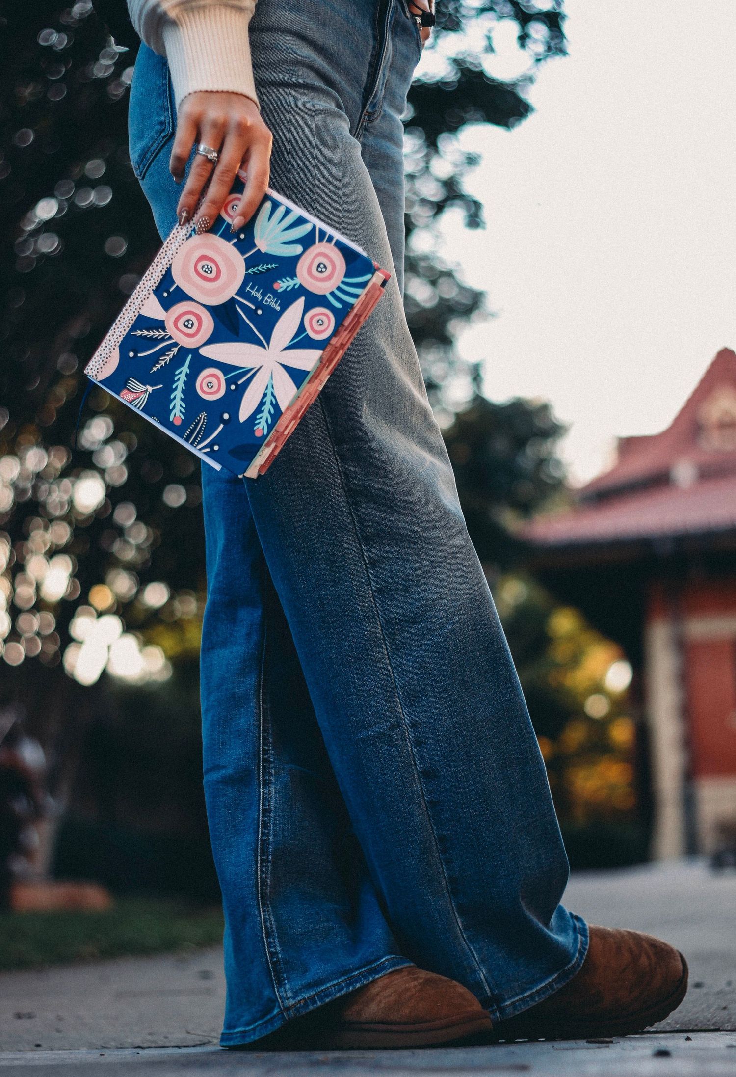 Close-up view of senior girl wearing jeans and brown boots holding her bible