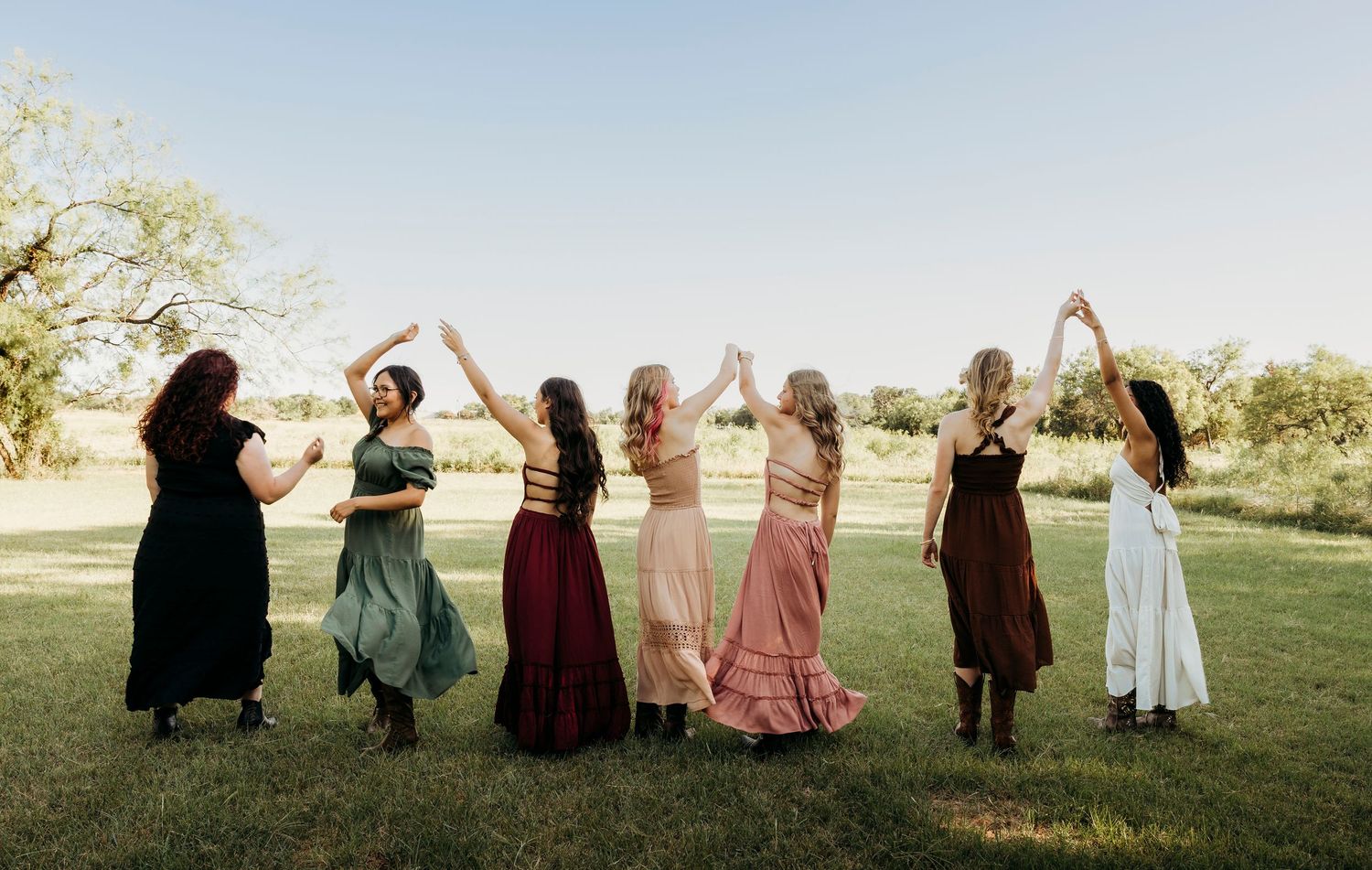 High school seniors spinning outside as their hair catches the golden sunset light during an outdoor senior session in Abilene, Texas