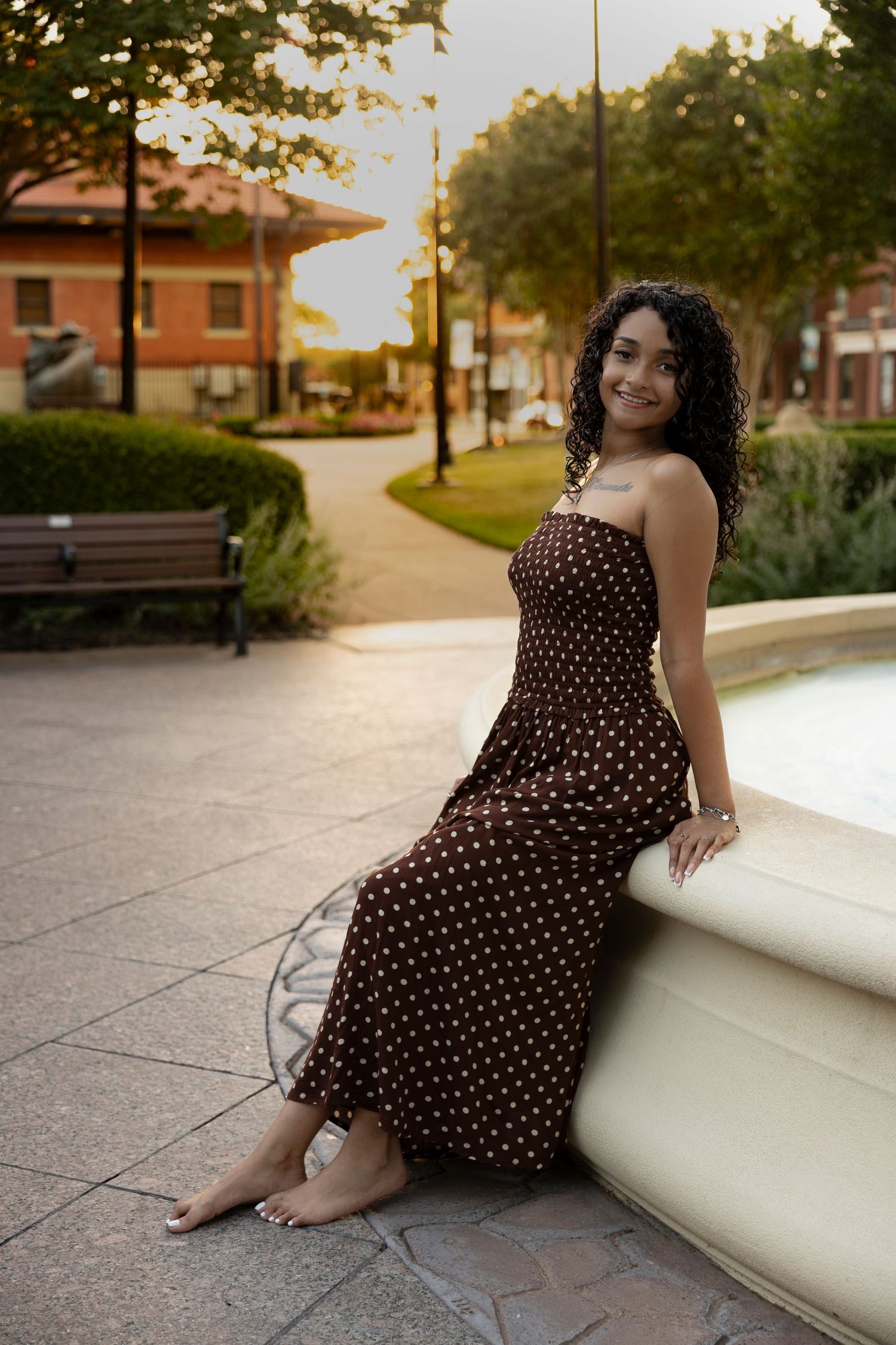 Cooper High School senior sitting beside a fountain in downtown Abilene, Texas during a golden hour senior portrait session.