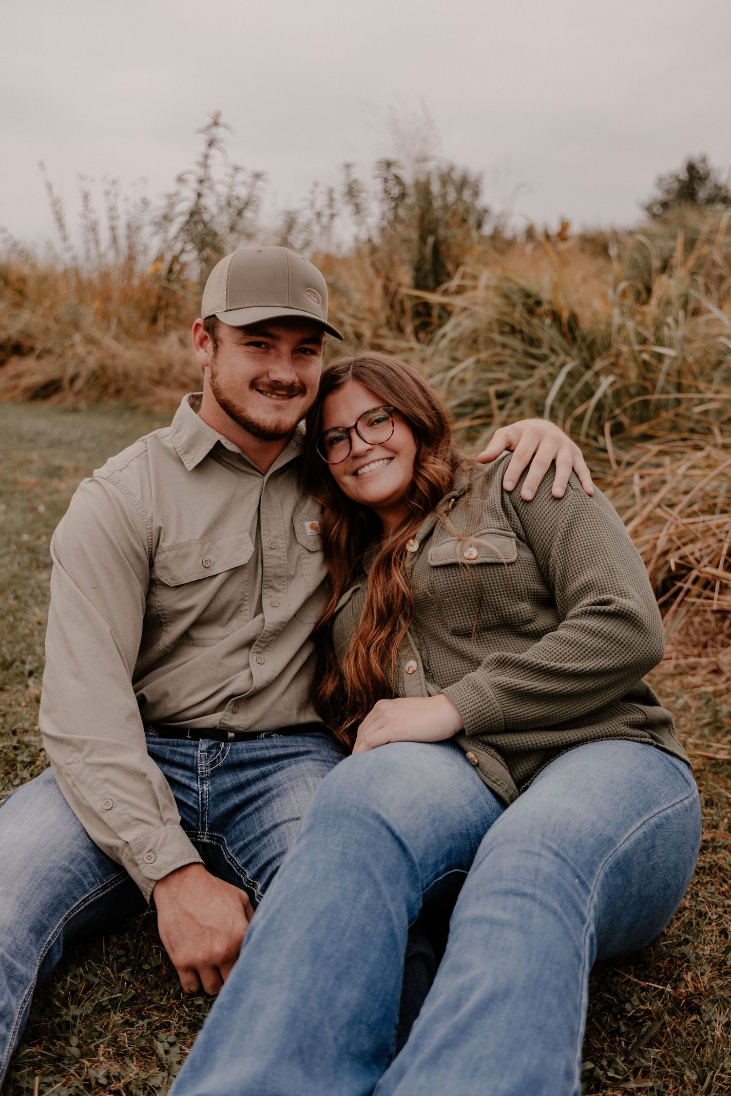 Couple sitting together on grass in casual outdoor setting.