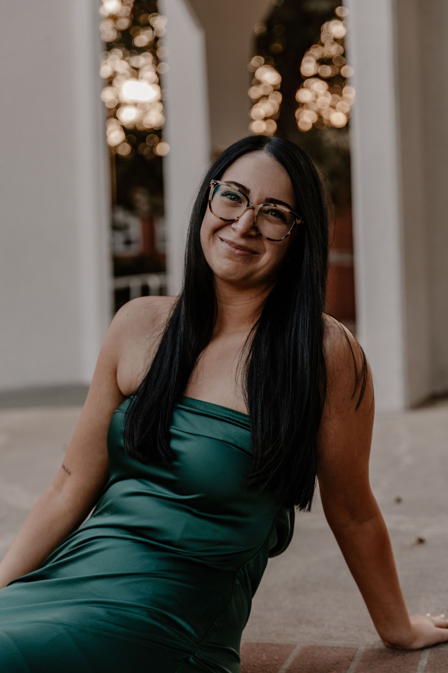 Graduation portraits of person in emerald dress with decorative lighting.