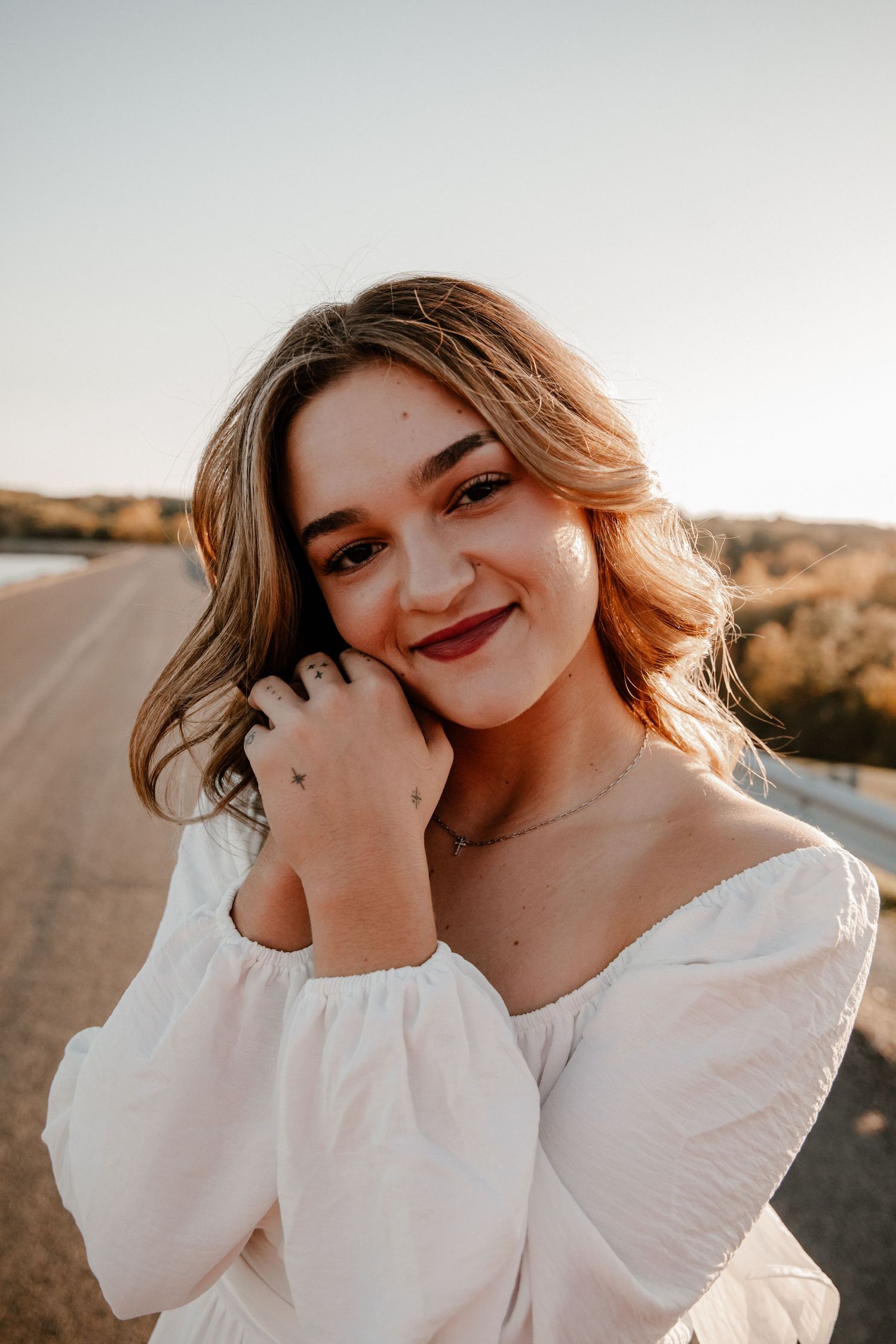 Close-up portrait in white sweater against desert landscape at golden hour.