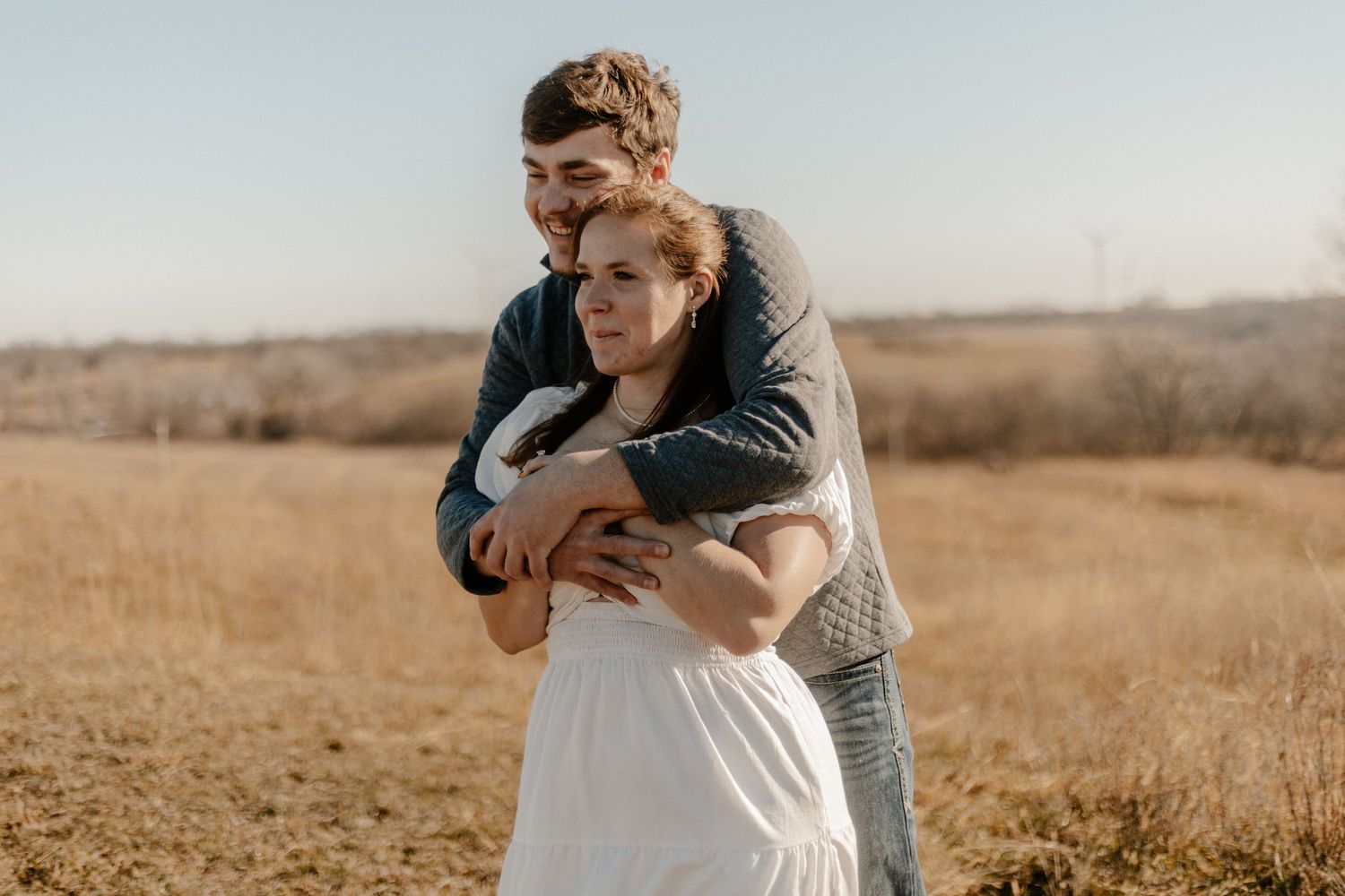 Couple posing in an open field during golden hour.