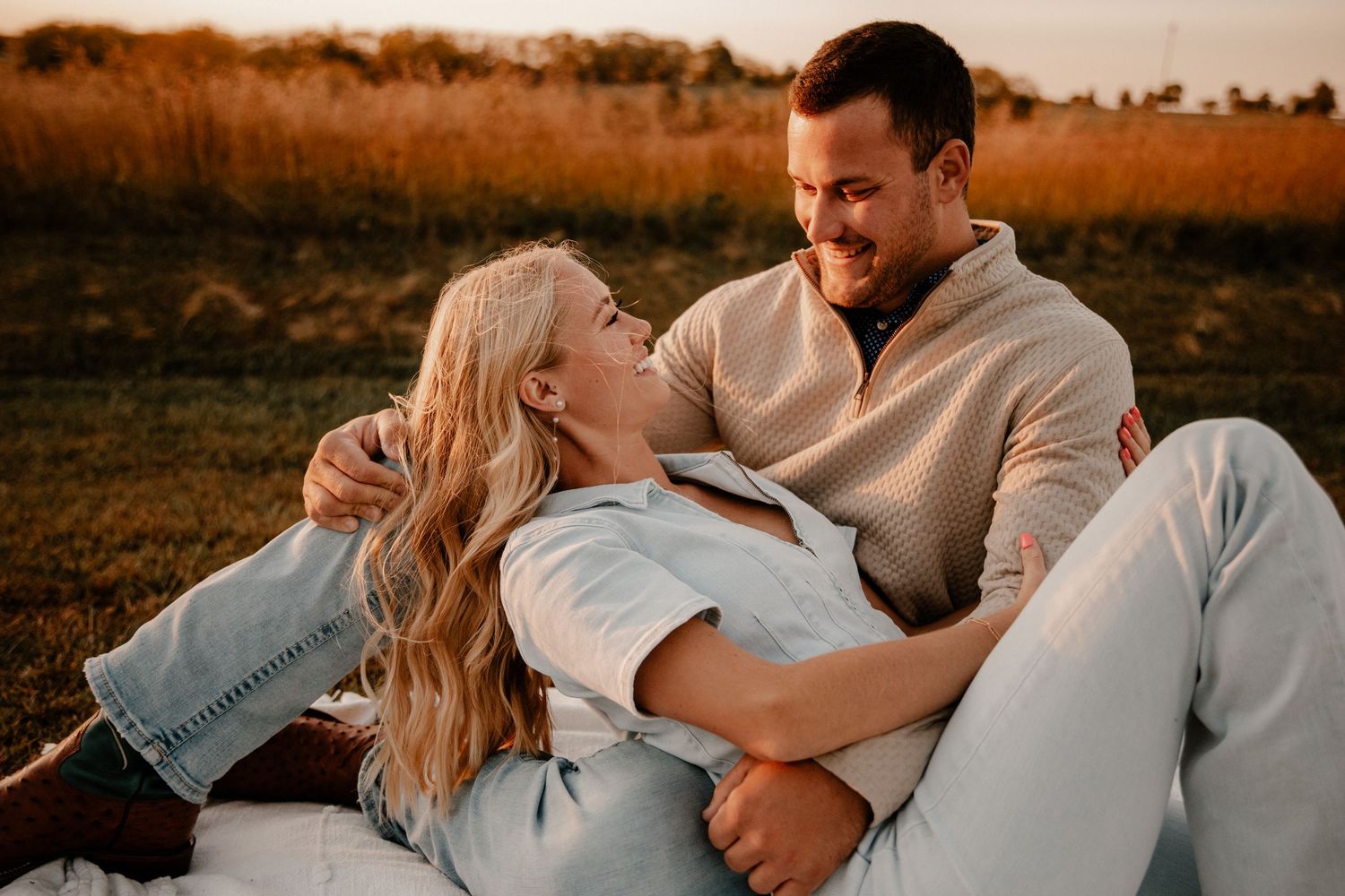 Couple sharing tender moment while relaxing outdoors during golden hour photoshoot.