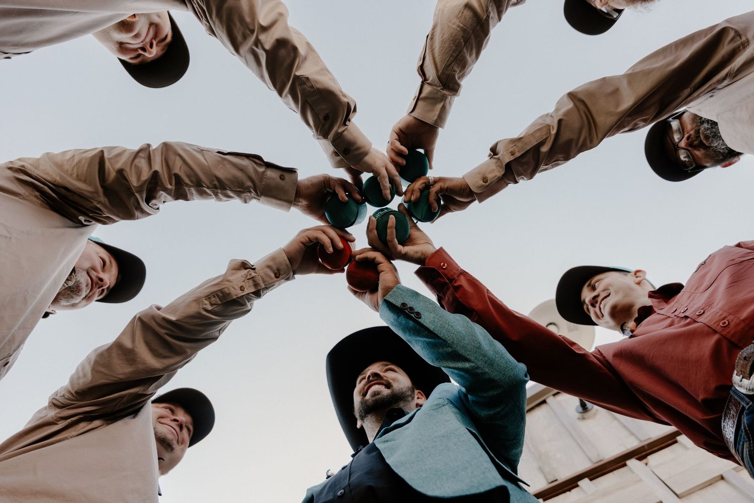 Group of friends forming a circle huddle from below perspective with hands joined in unity.