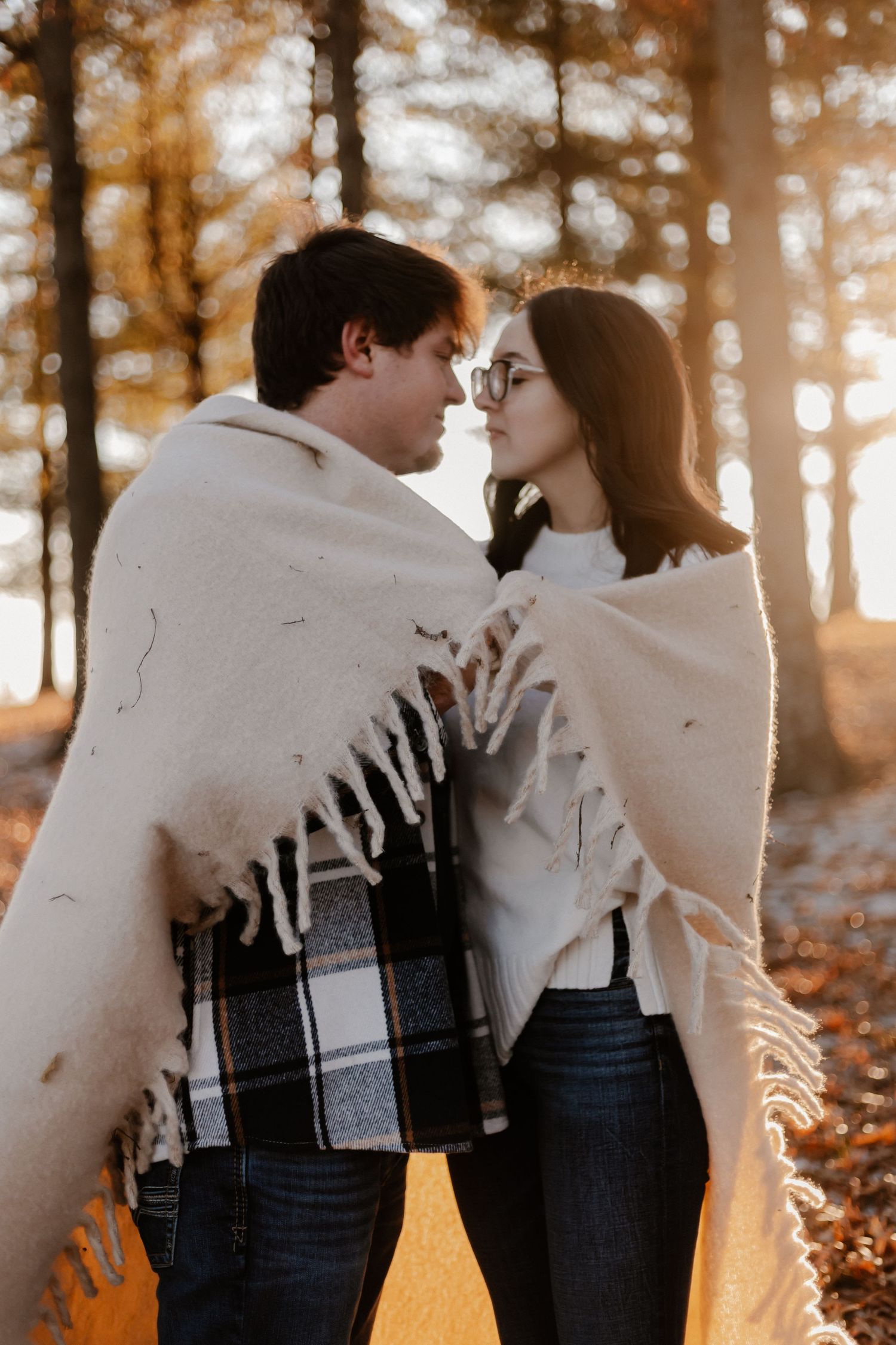 Romantic couple moment captured in silhouette against sunlit autumn forest.