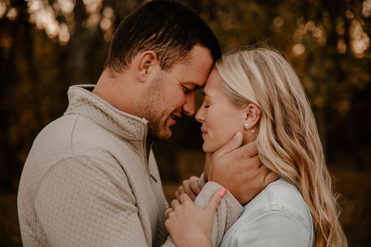 Romantic outdoor engagement photo with warm sunset lighting and intimate pose.