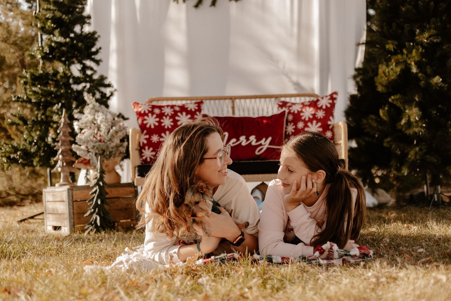 Two people laying on a blanket outdoors during a holiday photo session with festive decorations.