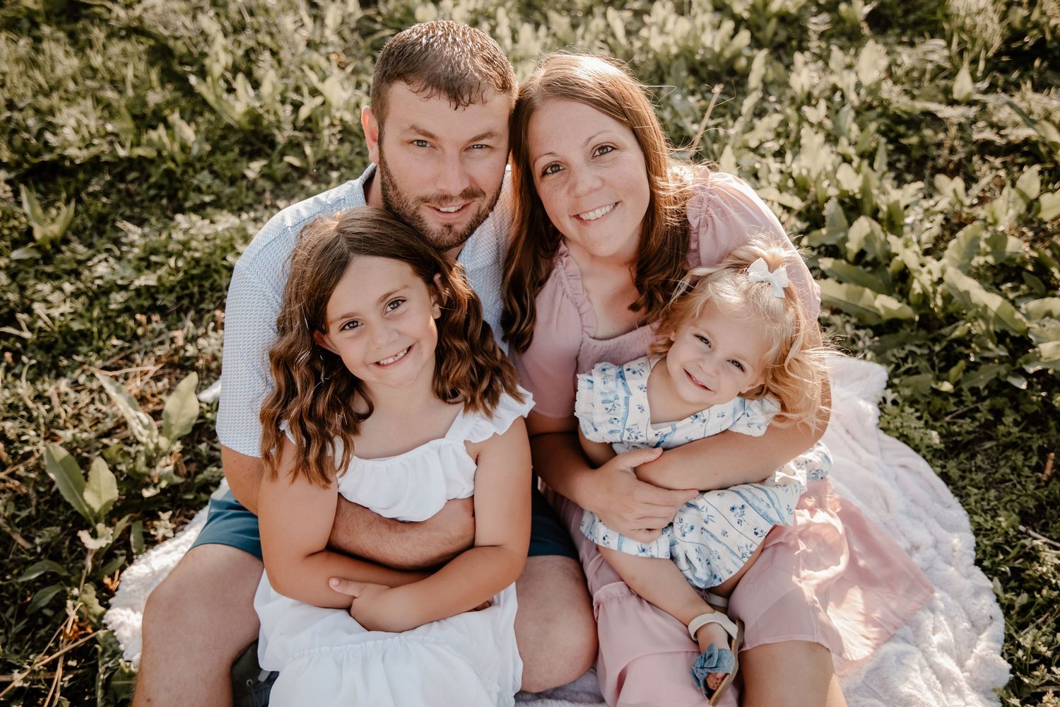 Family of four posing together for outdoor portrait during spring or summer day.