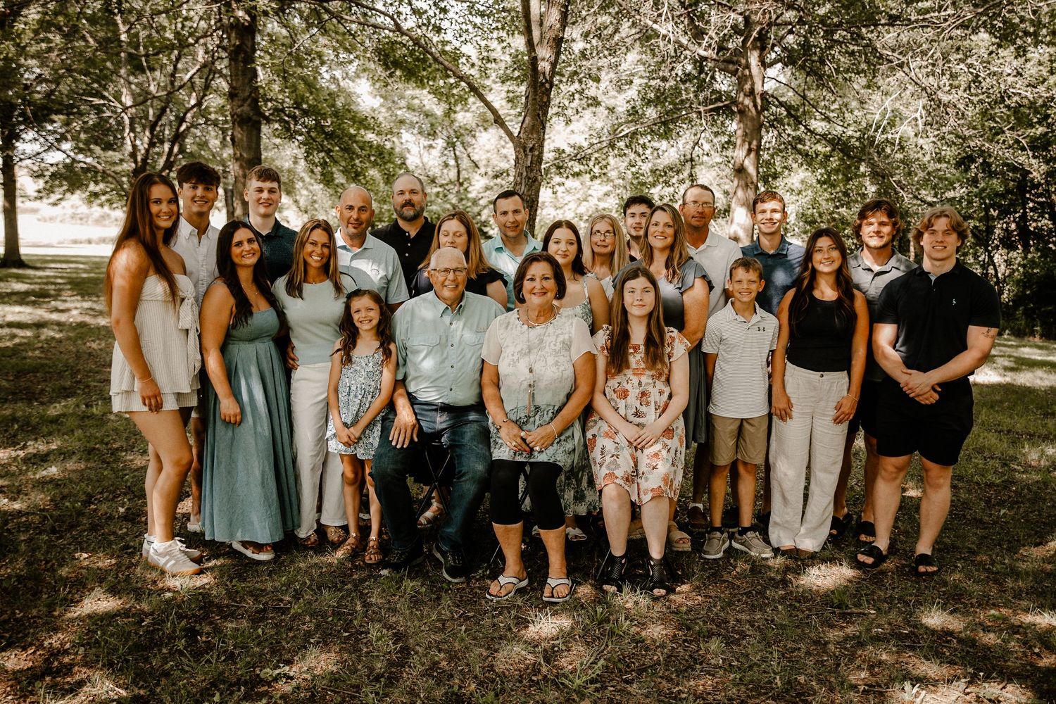 Extended family group photo session in natural outdoor setting with coordinated outfits.