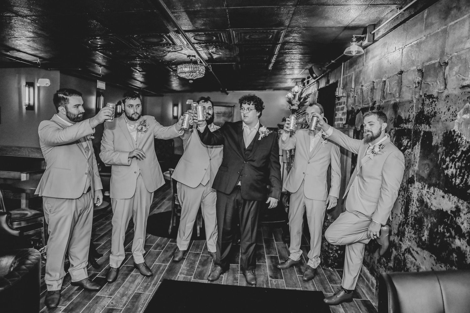 Black and white photo of a wedding party dancing and celebrating in a dimly lit venue.
