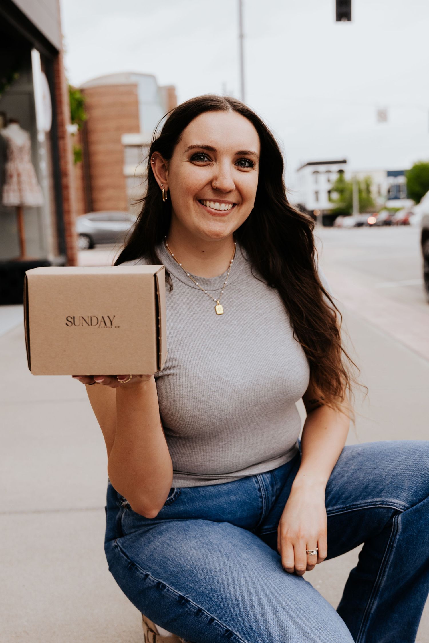 Smiling woman holding Sunday branded box outdoors.