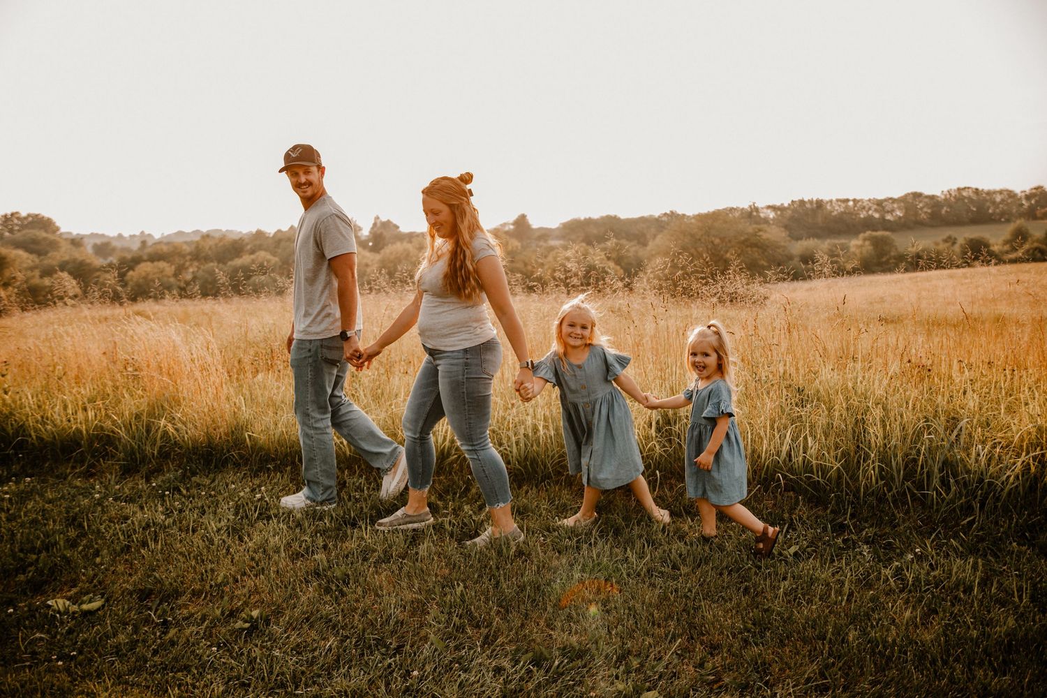 Family group relaxes together in a sun-drenched field wearing coordinated casual outfits.