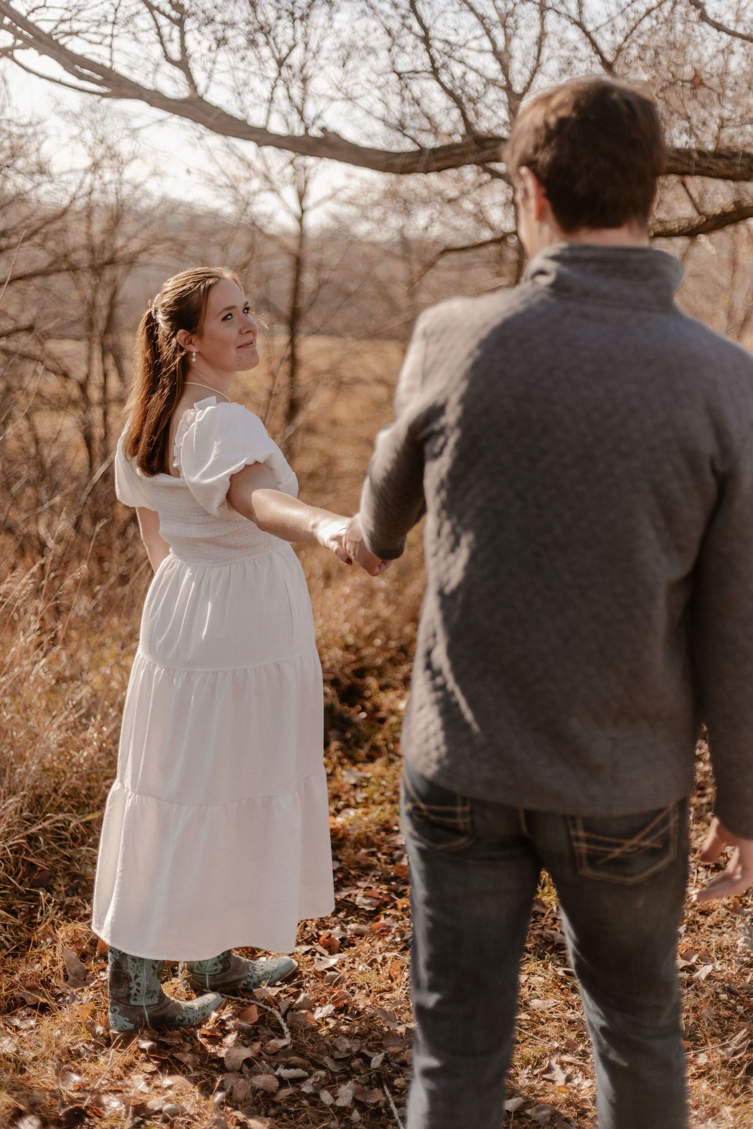 Couple walking through fallen leaves in autumn scenery.