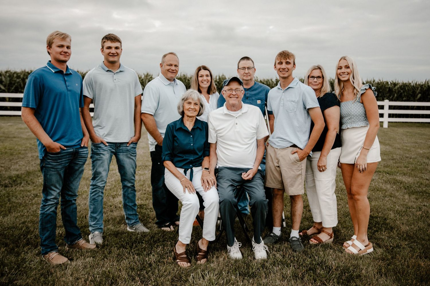 Extended family members gather for a casual outdoor photo shoot in coordinated casual attire.
