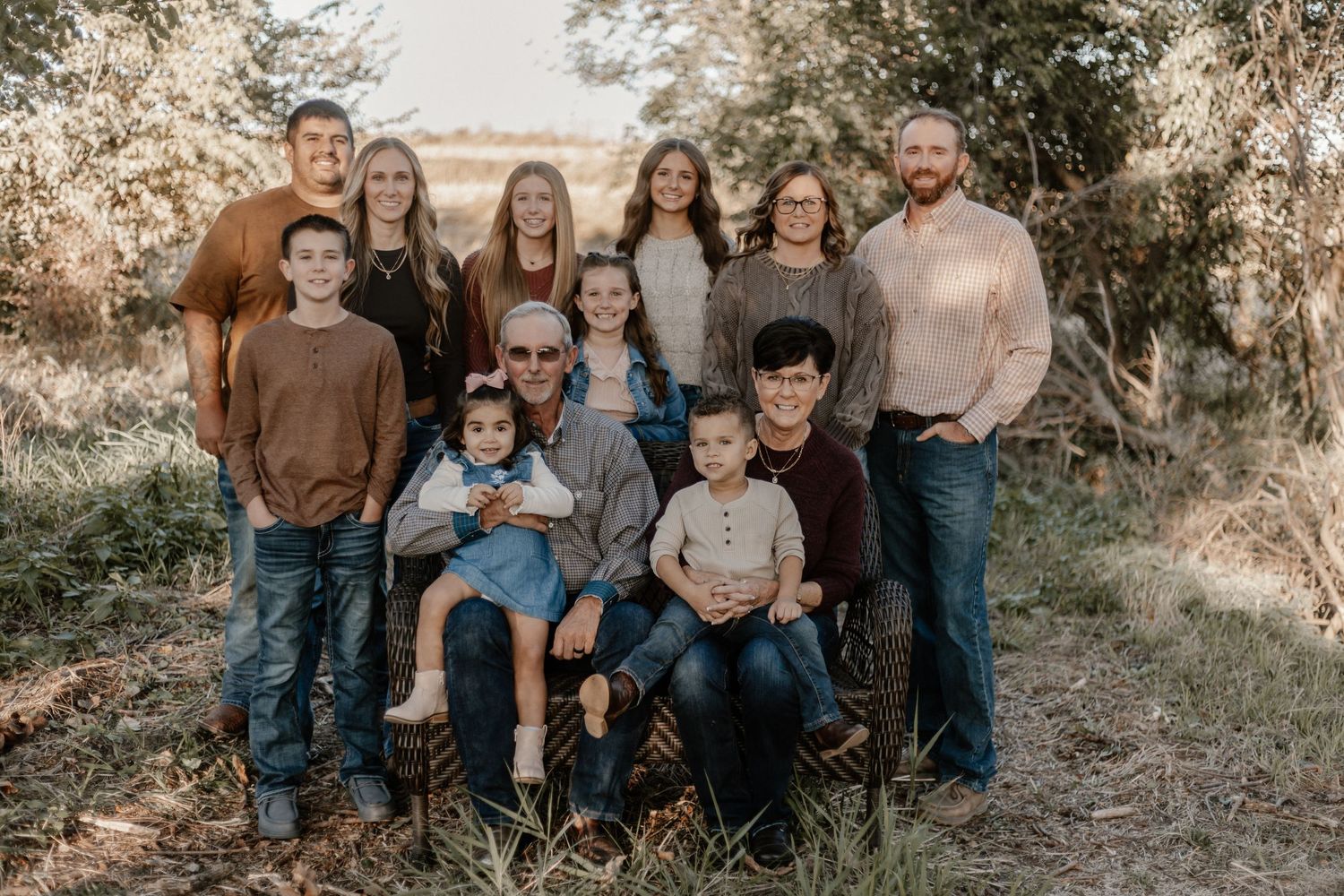 Large family group posed together outdoors in casual clothing during autumn photoshoot.