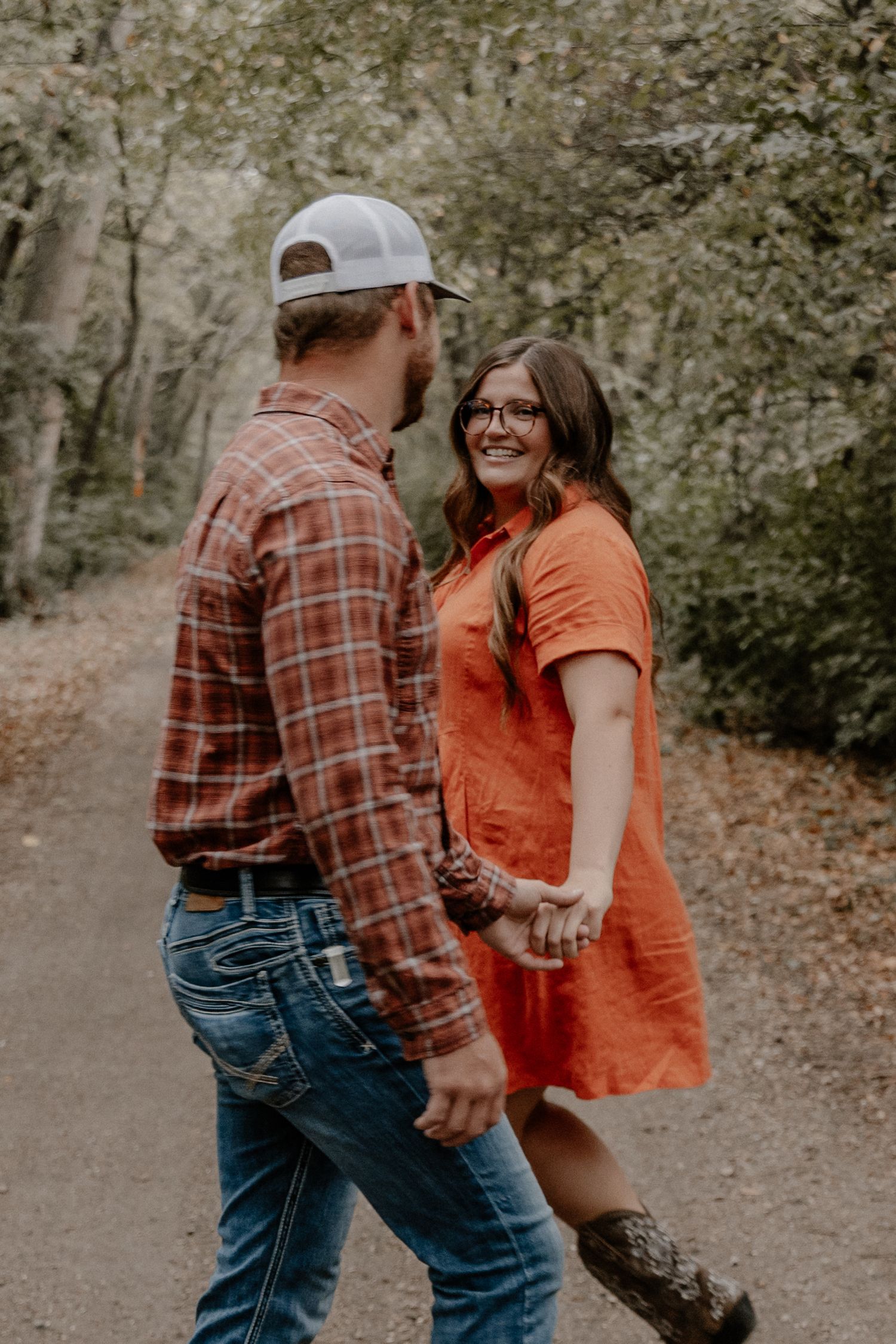 Playful couple walking together on autumn path.