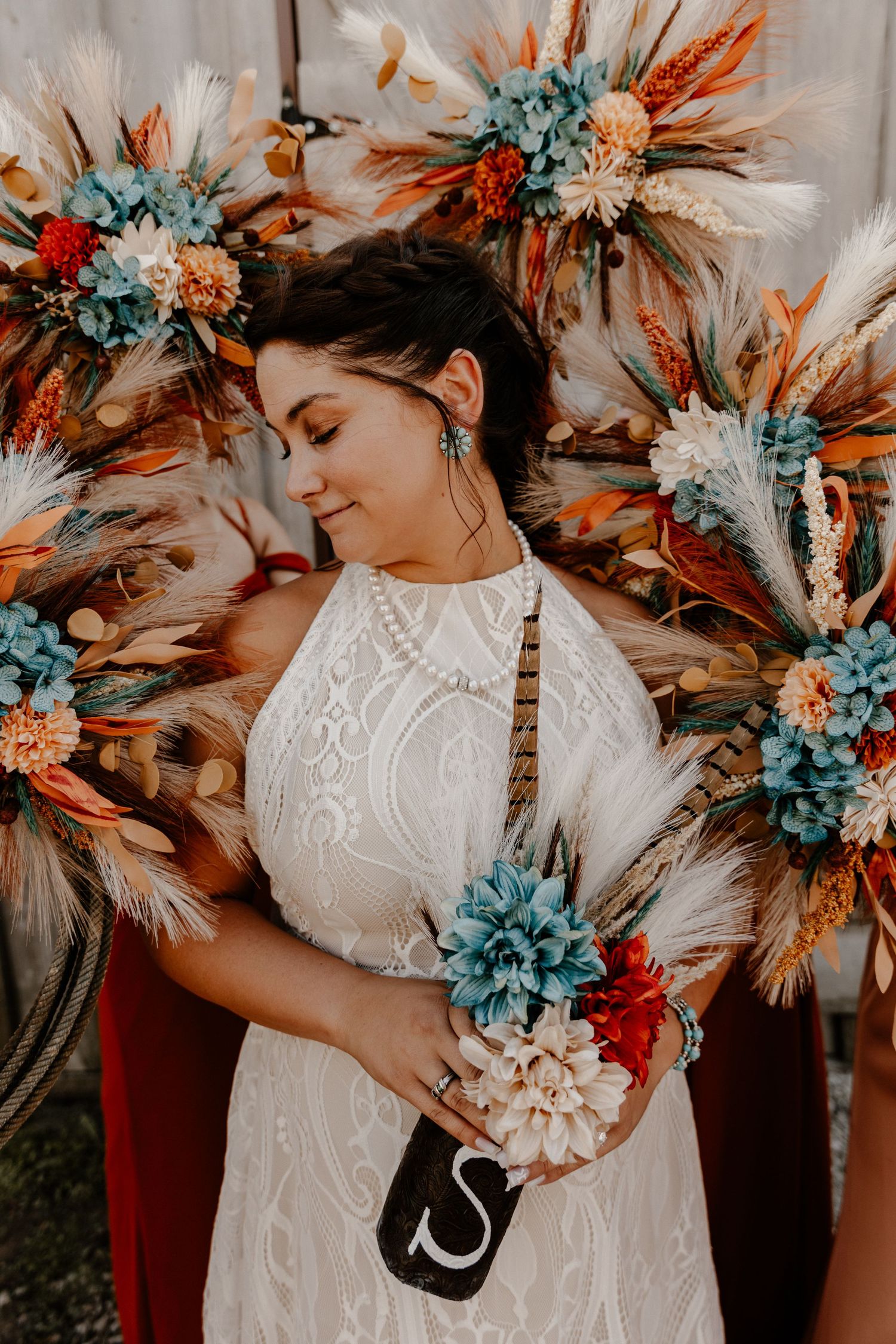 Bridal bouquet features vibrant orange and blue flowers with modern dried elements.