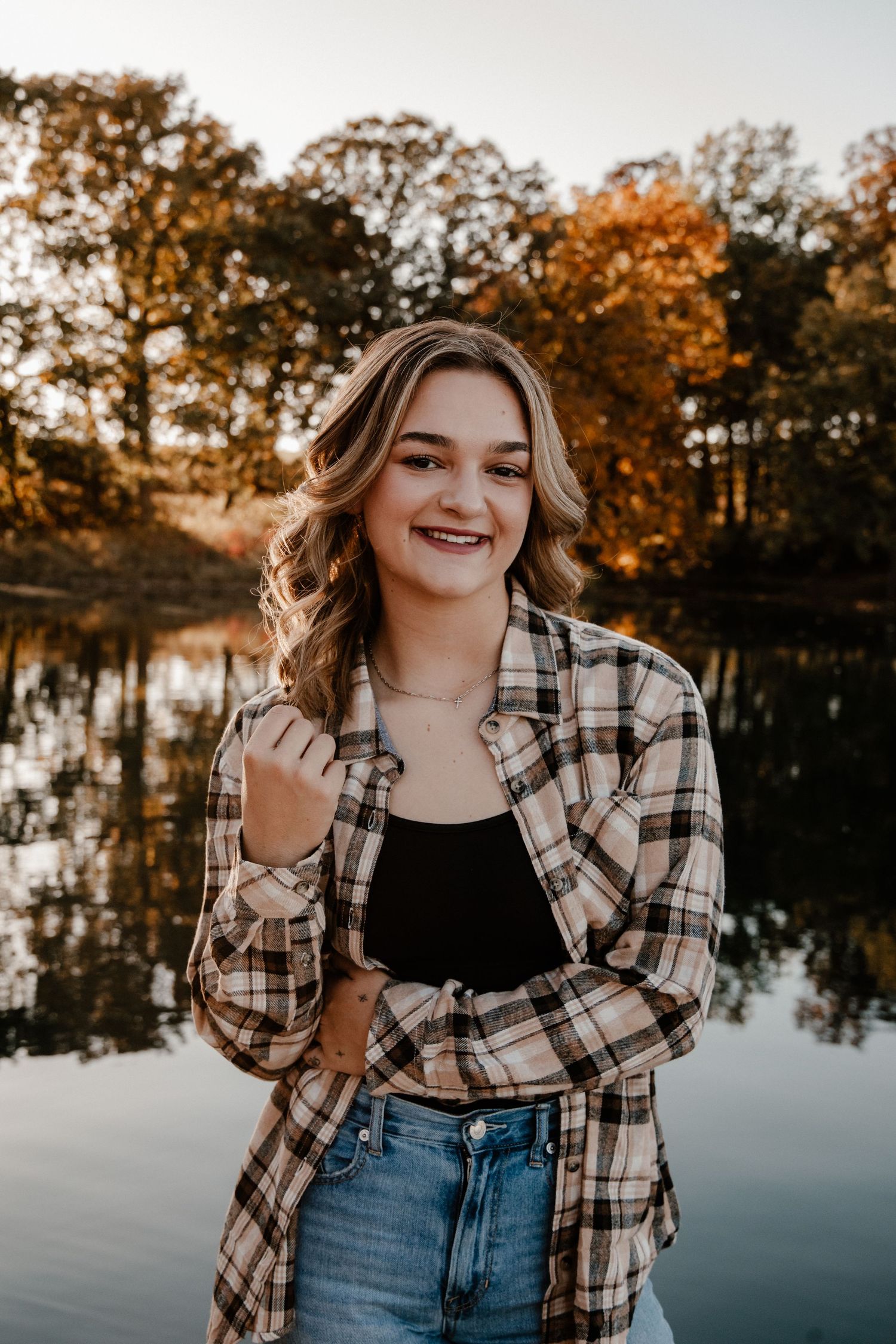 Lakeside portrait session wearing plaid flannel and jeans at sunset.