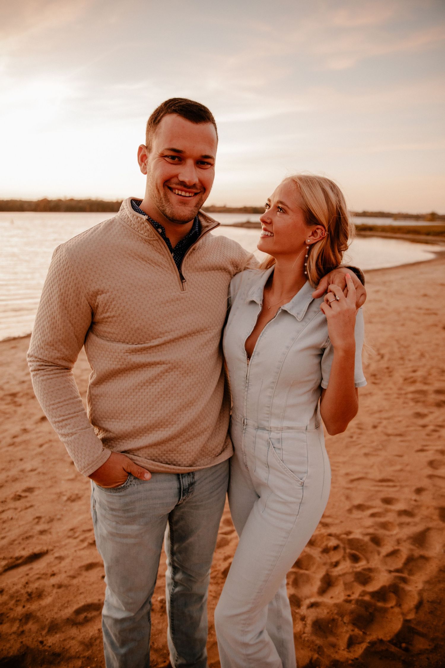Happy couple posing on beach during golden hour photoshoot.