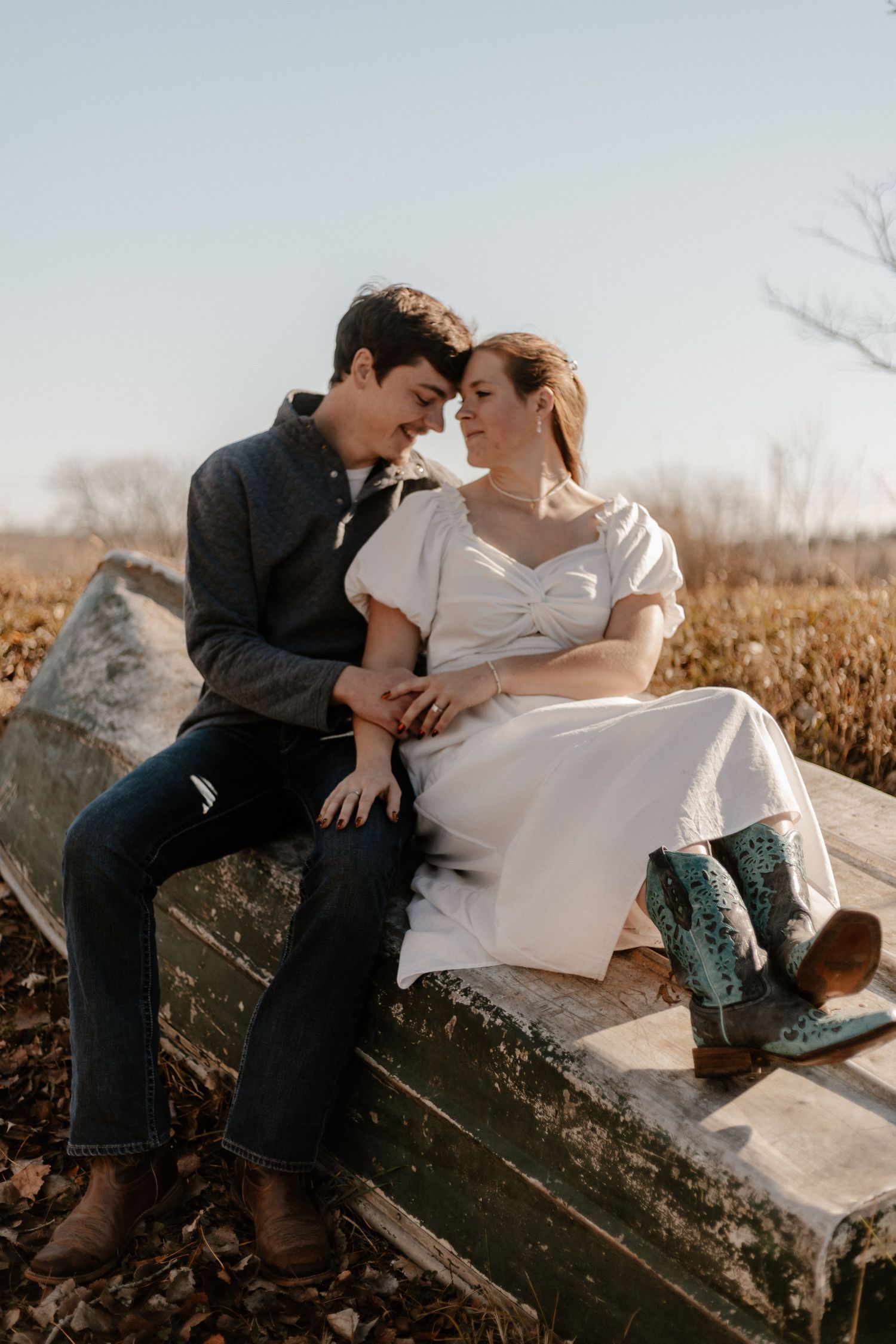 Couple sharing intimate moments while sitting on wooden fence in rural setting.