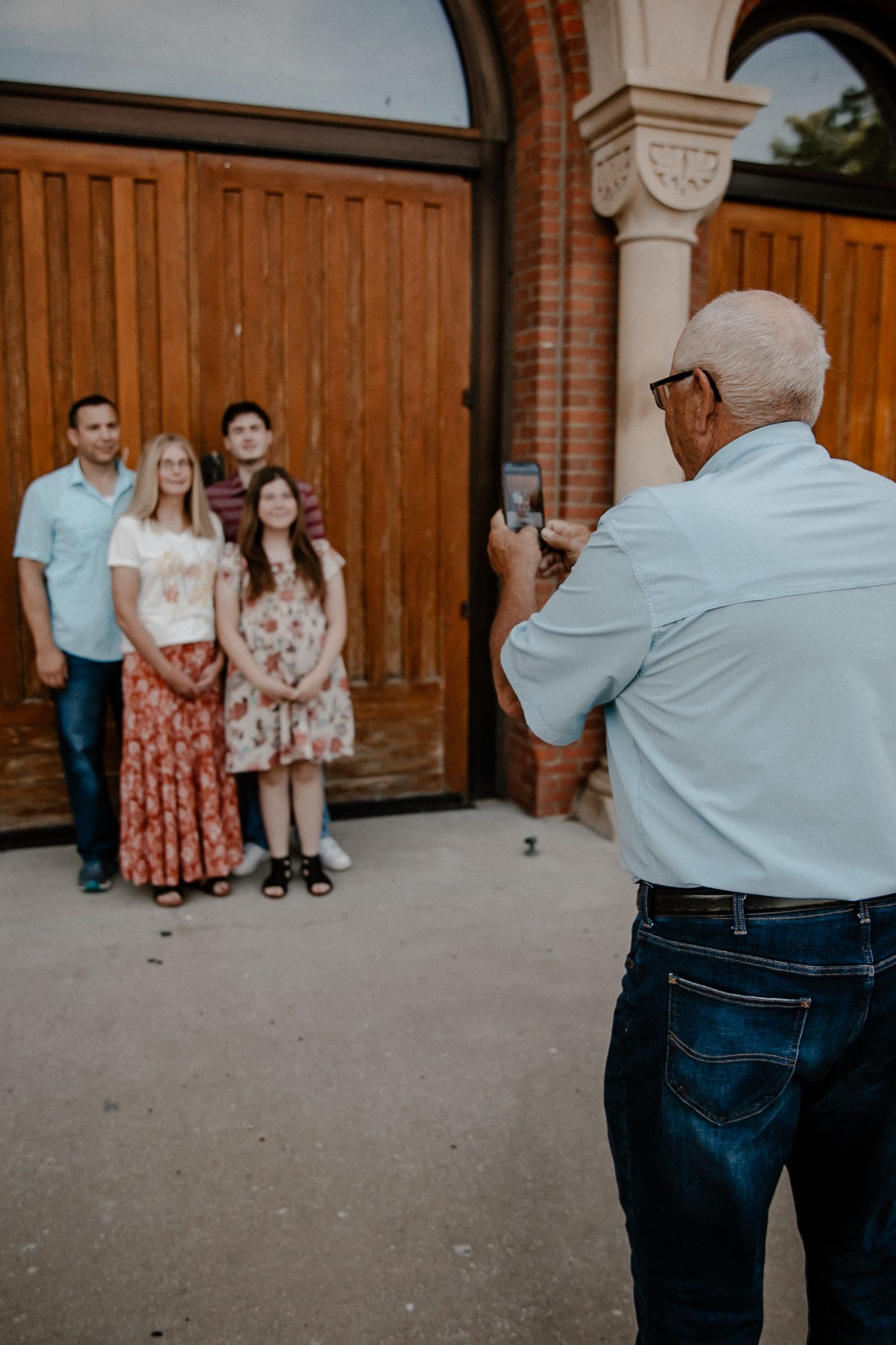 Behind-the-scenes view of photographer capturing family portrait at historic brick building.