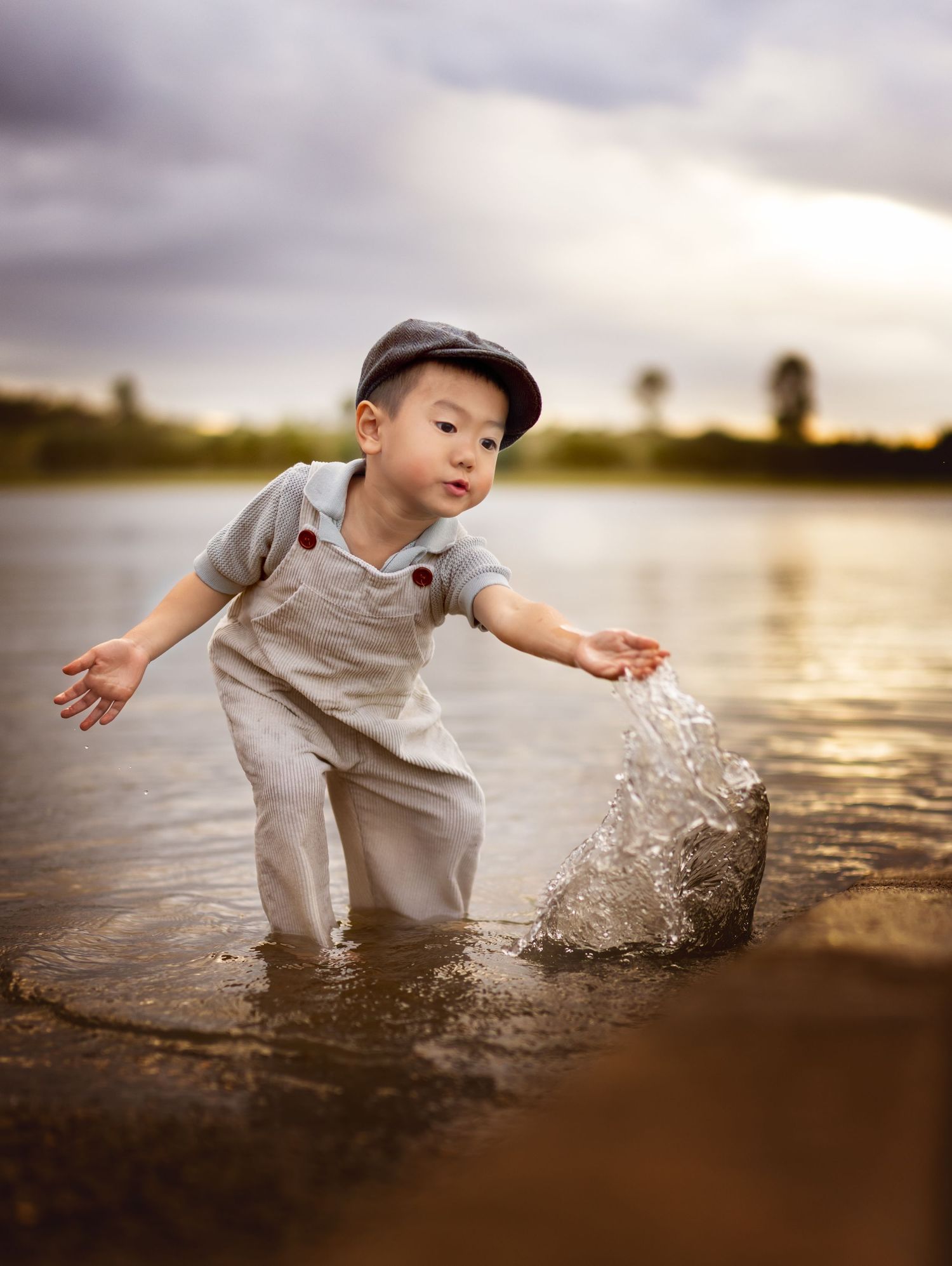 Candid child photography at sunset - Little boy playing with water in Brisbane lake, fine art style.