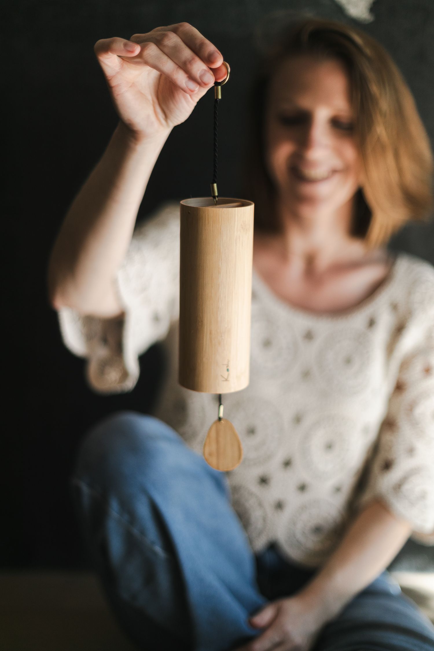 Praticienne de massage bien-être tenant un carillon koshi en bambou pour un séance de relaxation après un massage.