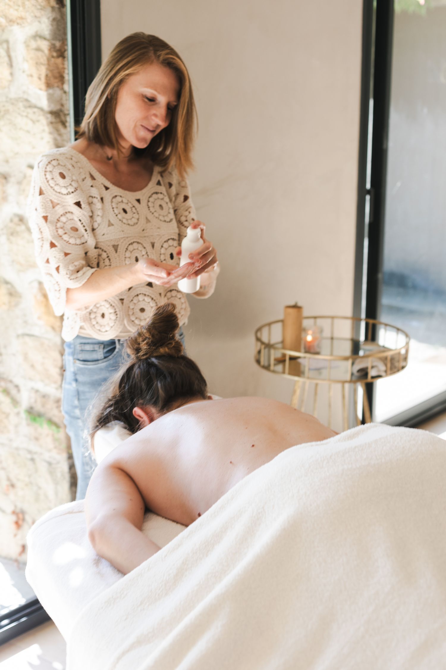 Praticienne en massage bien-être douce et souriante entrain de préparer son huile de massage avant de donner un massage intuitif.