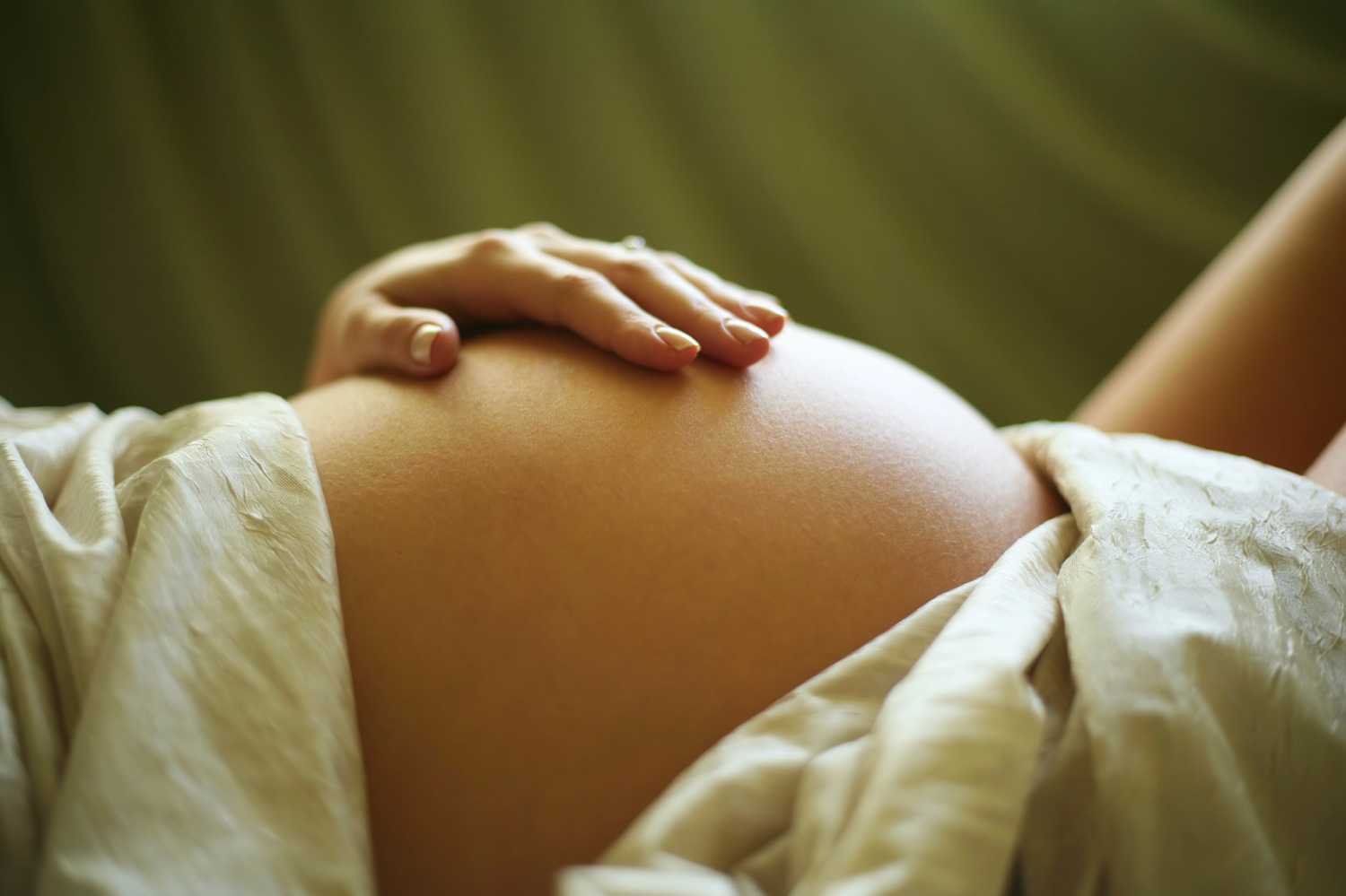 Massage femme enceinte dans l'ouest lyonnais : main posée sur le ventre, soin prénatal doux pour détente, bien-être et connexion avec bébé