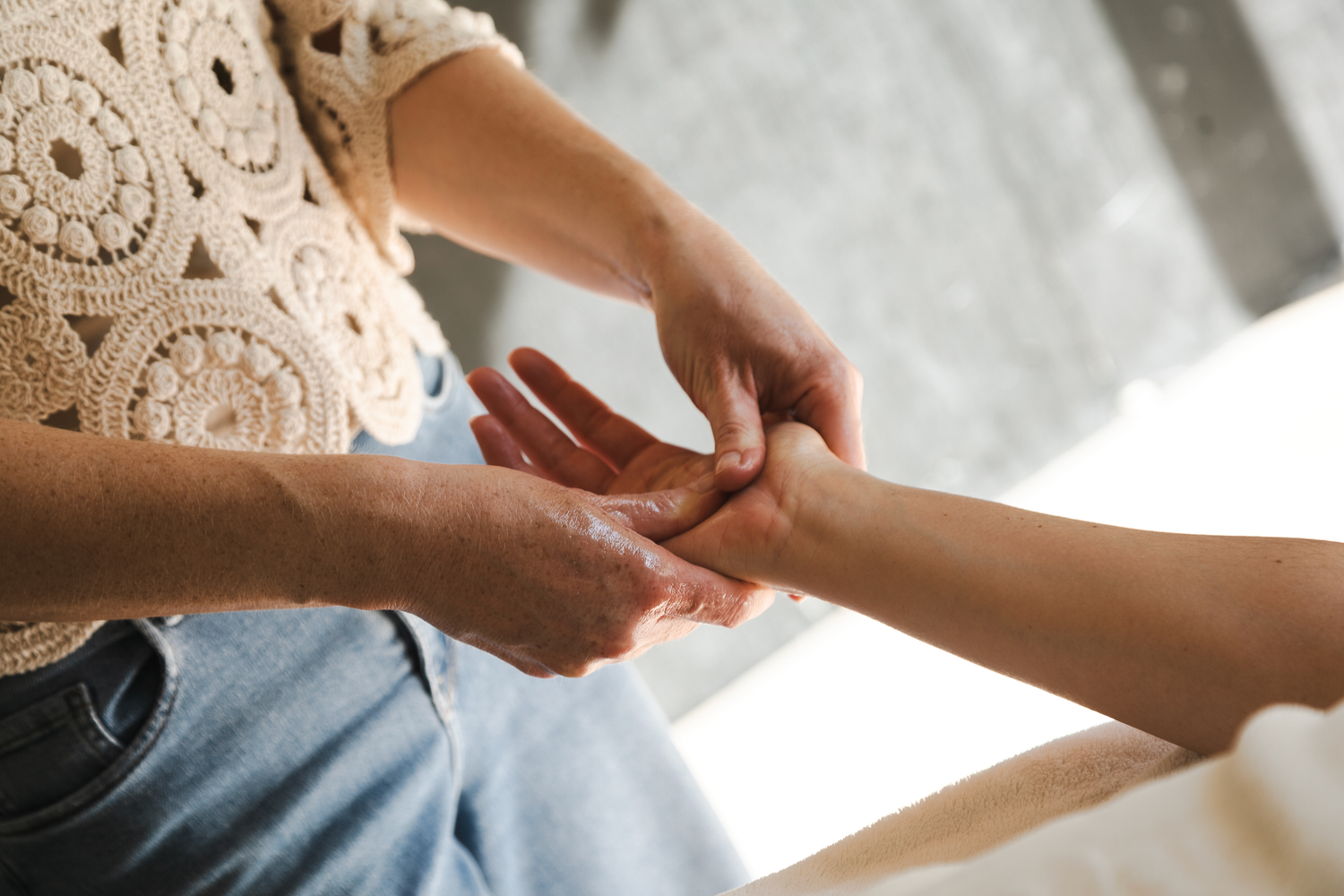 Praticienne massant la main de sa cliente avec ses pouces. Massage des mains à l'huile pour un profond moment de relaxation et de détente.