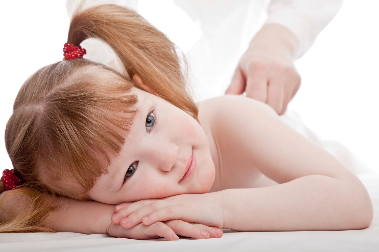 Petite fille pensive et souriante entrain de recevoir un massage doux et bienveillant. Bien-être de l'enfant calme et apaisé.