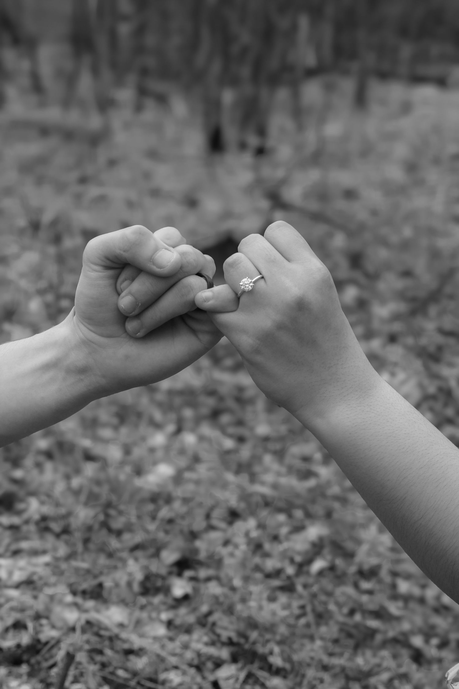 Black and white sequence of two hands making a pinky promise gesture against a blurred outdoor background.