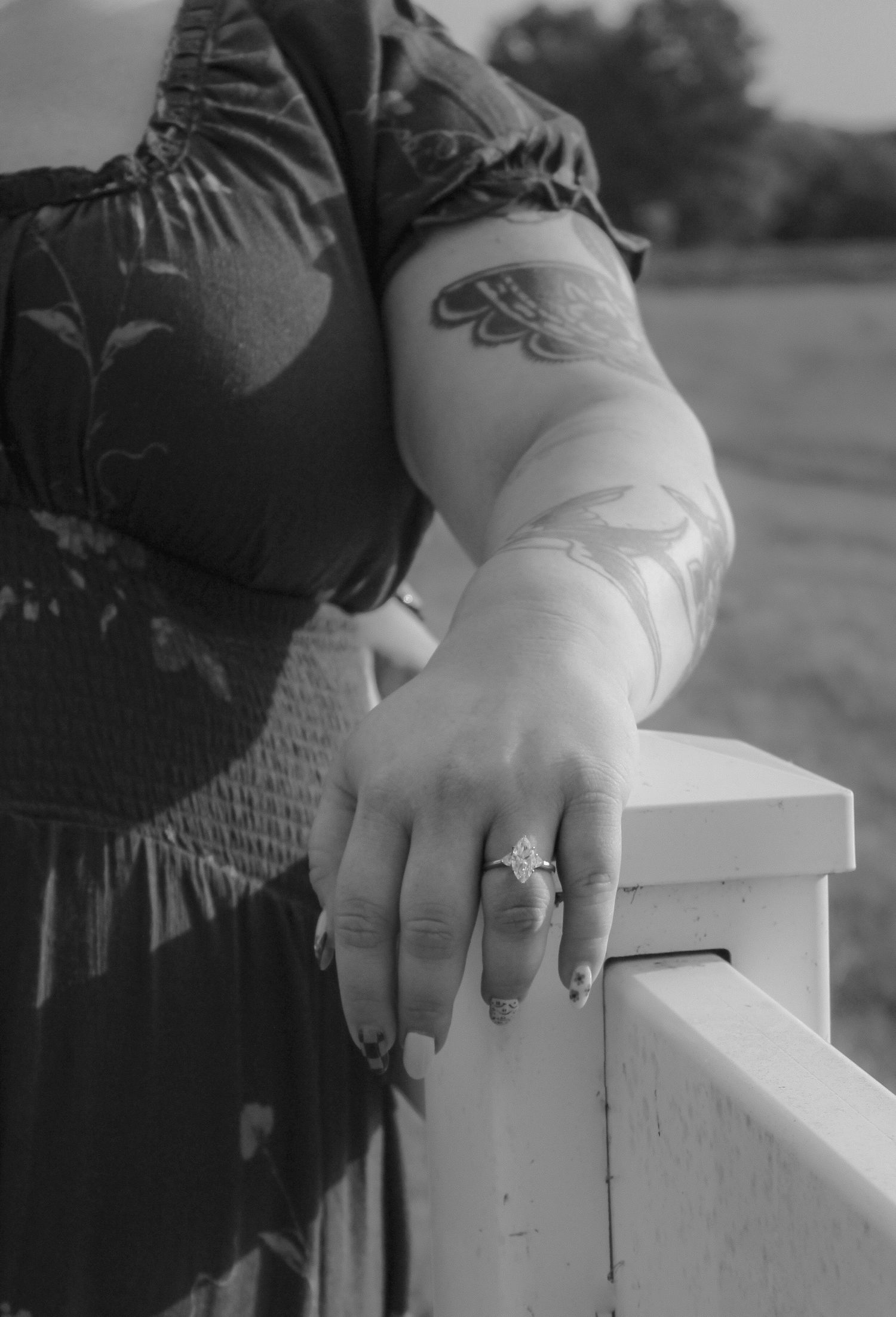 A close-up series of black and white photos showing hands wearing an engagement ring resting on a white railing.