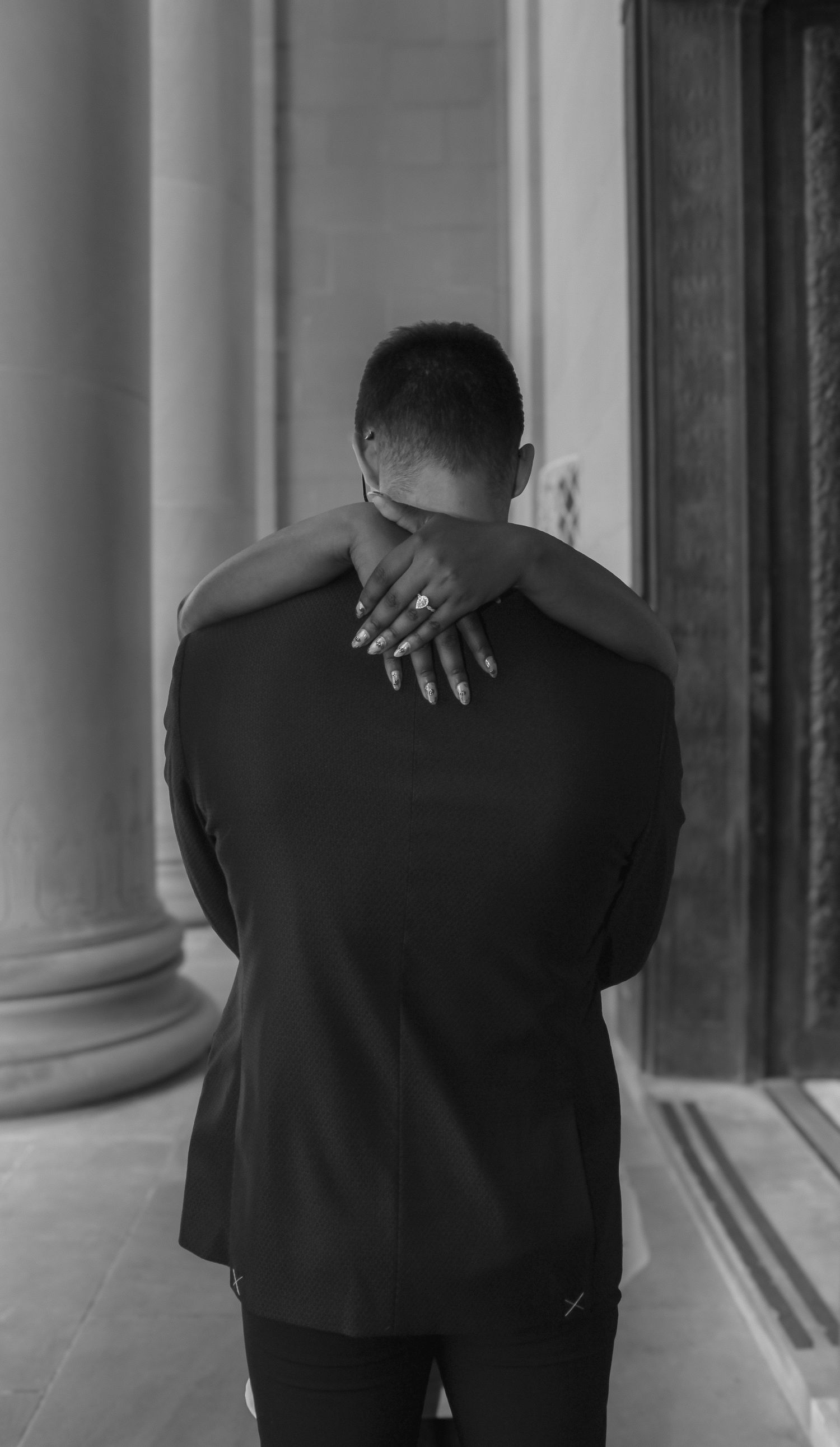 A series of black and white photographs showing the back of someone wearing a dark suit in a columned hallway.