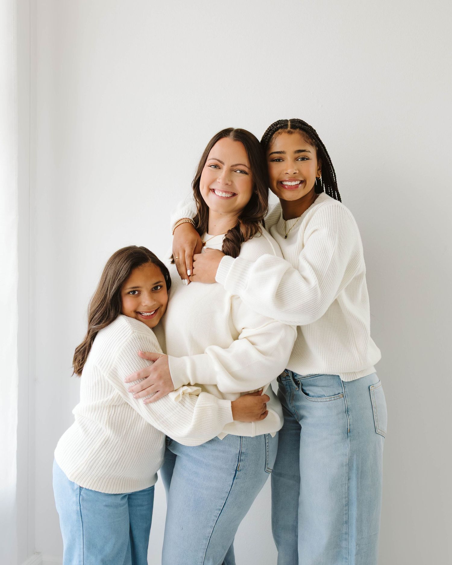 Mother and daughters hugging each other in all white natural light studio- St. Louis family Missouri family session