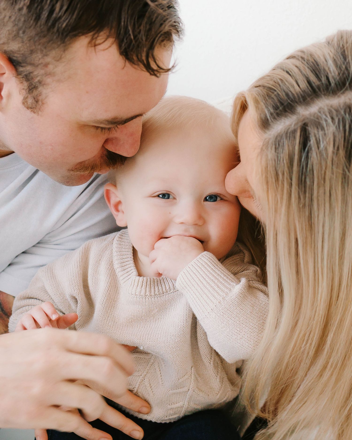 Family snuggling and kissing baby in natural light studio- St. Louis family photography