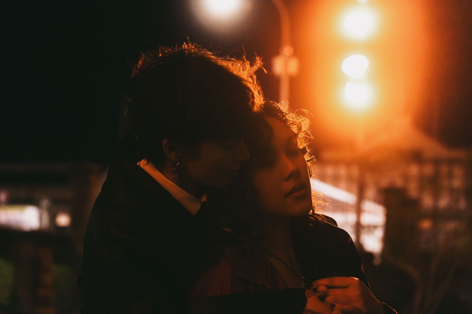 Moody nighttime portraits illuminated by warm ambient lighting.