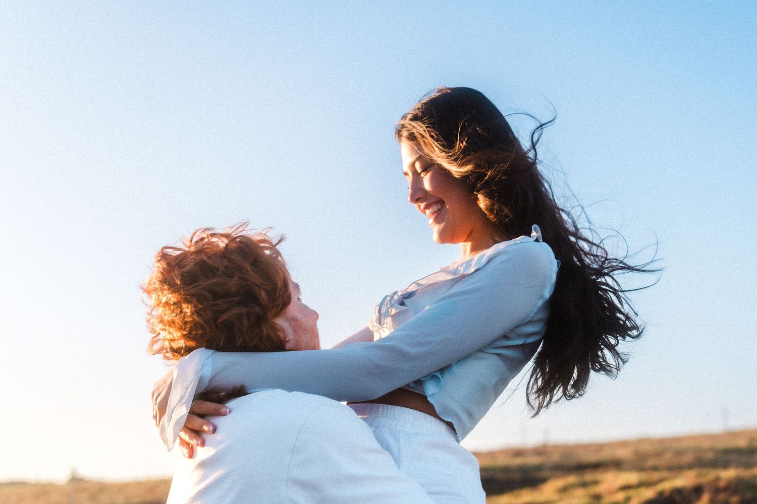 A couple spins joyfully together outdoors.