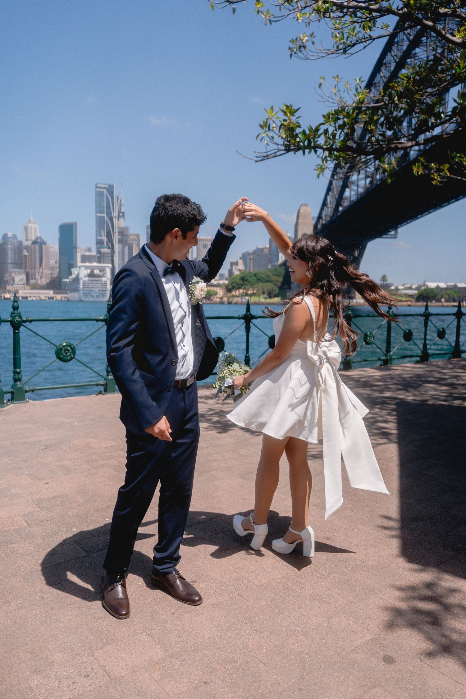 Playful dance sequence on a beach with city skyline in background.