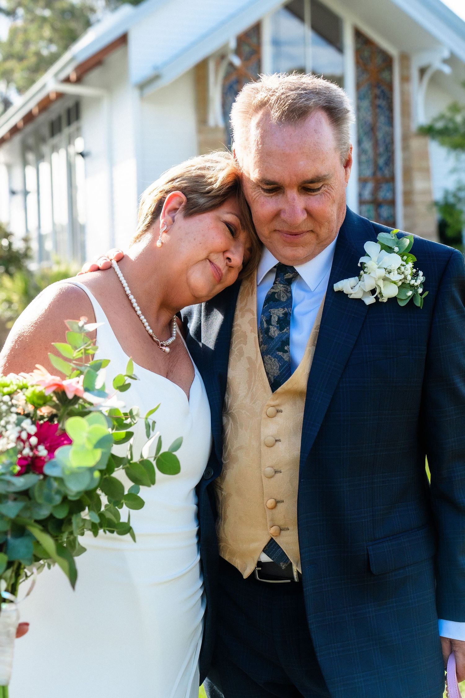 Wedding couple sharing intimate moments outside a chapel with white walls.