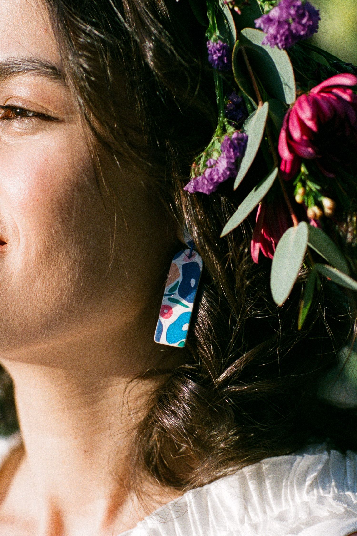 Colorful floral arrangement with purple and pink blooms adorning a decorative earring.