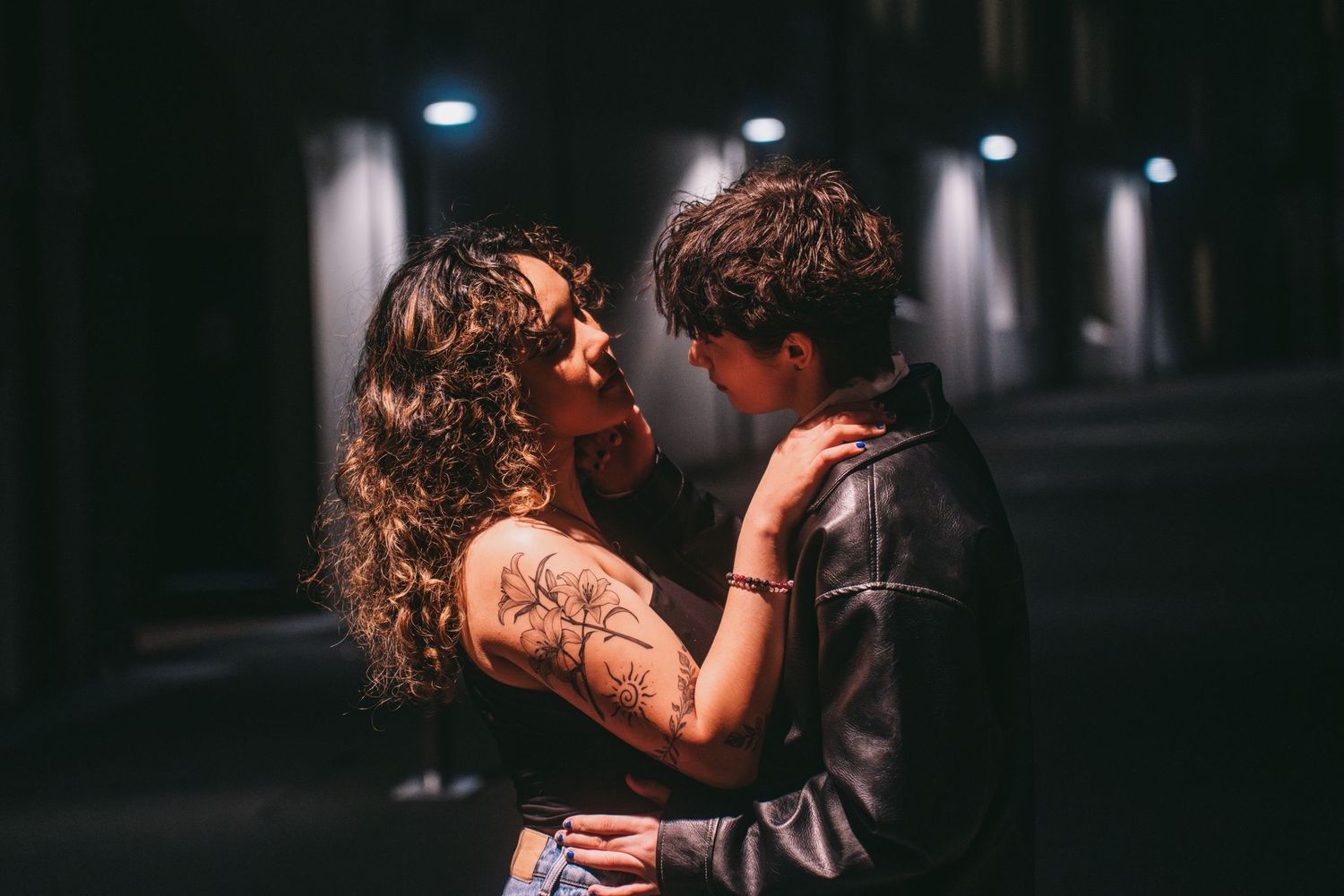 A romantic nighttime scene with two figures silhouetted against dark lighting.