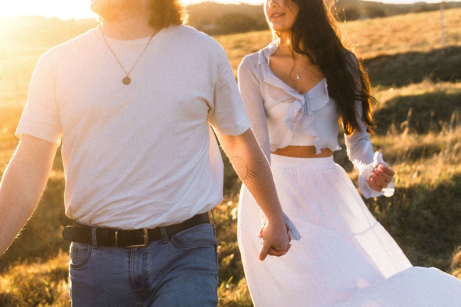 Sun-drenched photos of a couple dancing and embracing in a meadow at golden hour.