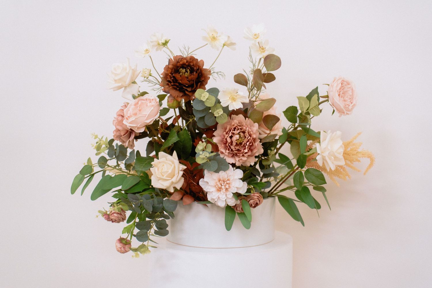 Delicate floral arrangements featuring pink roses and greenery on a white surface.