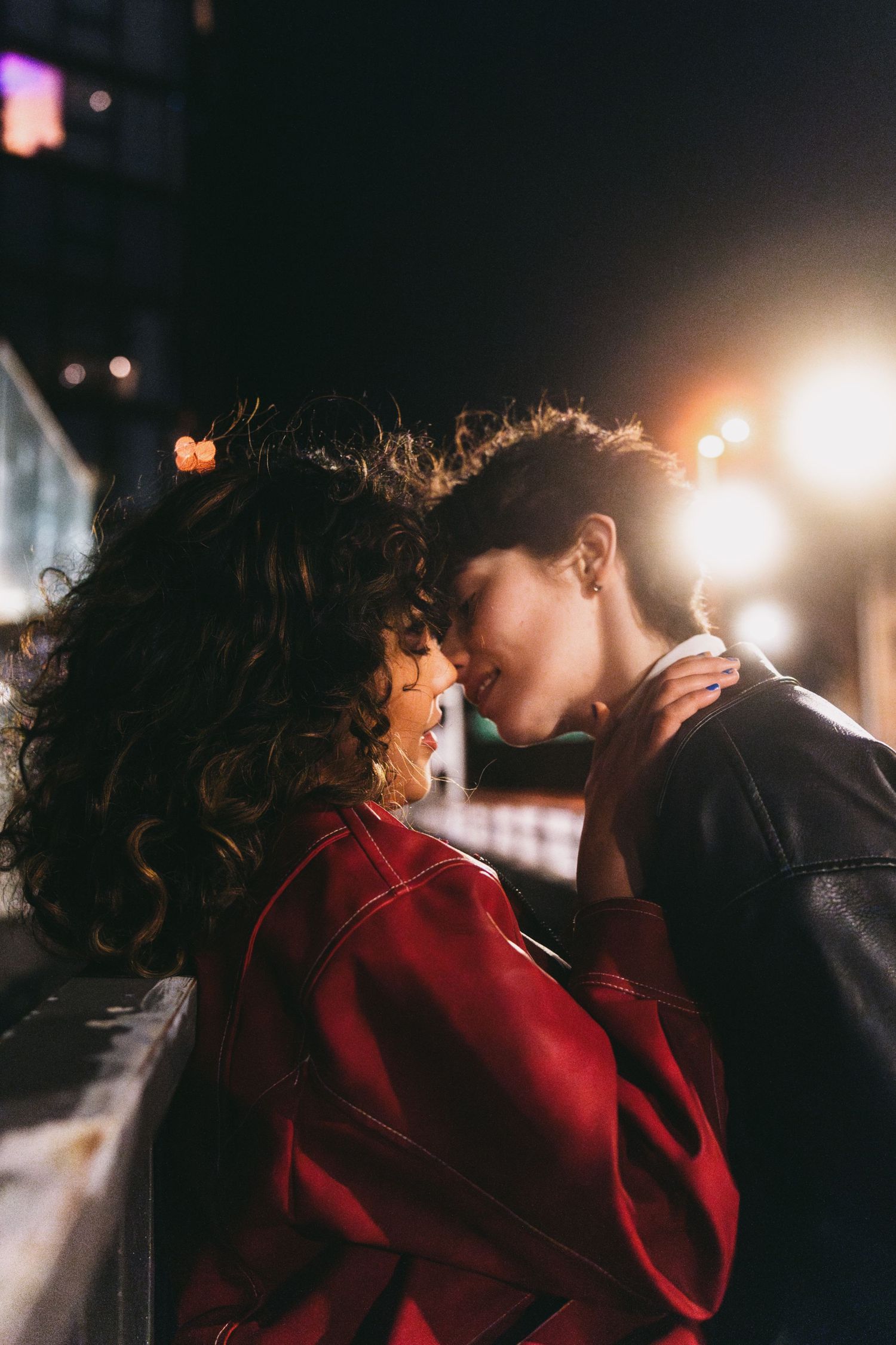 Two people in close proximity under moody nighttime lighting.