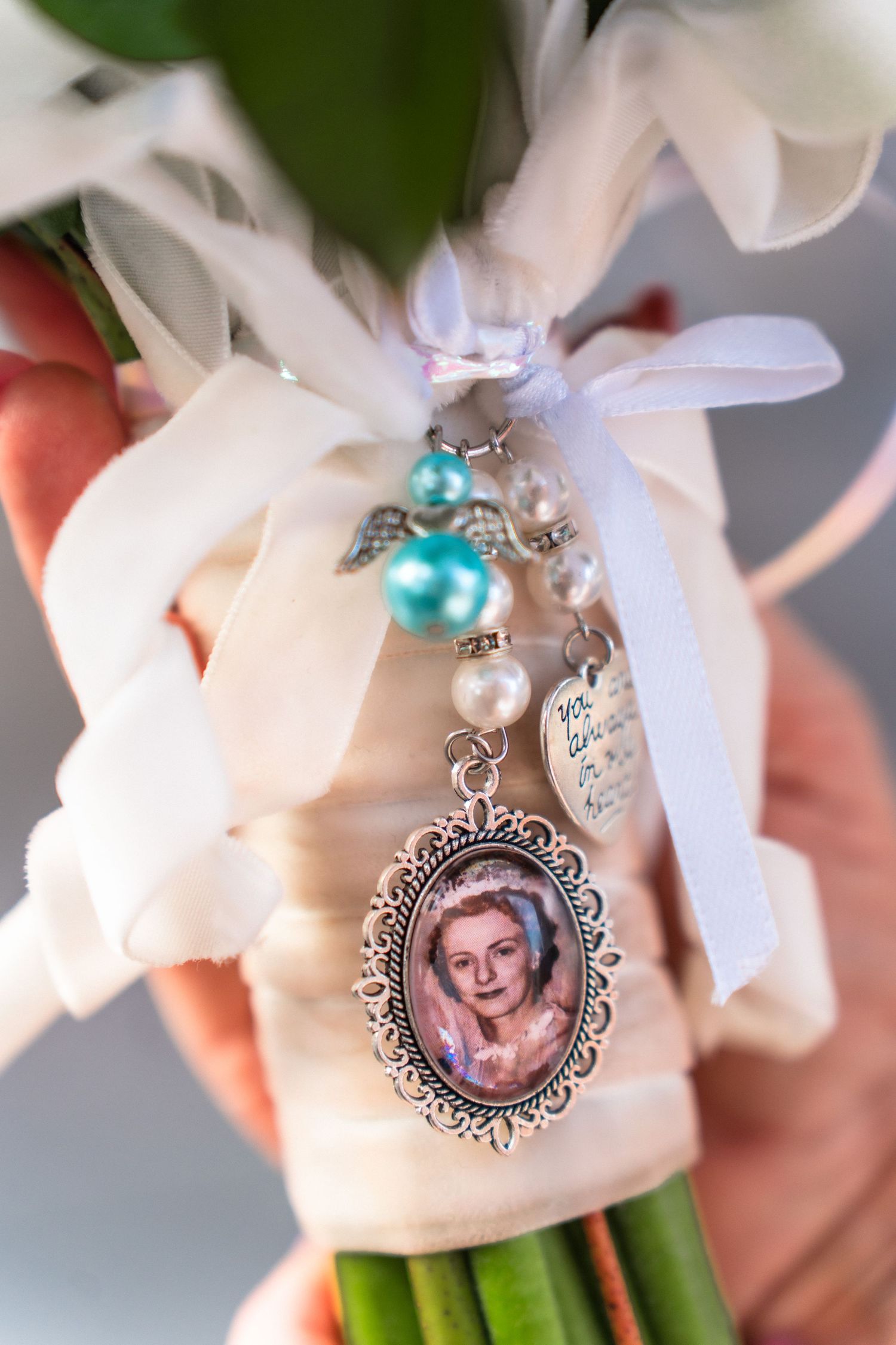 Wedding bouquet decorated with memorial photo charms and turquoise accents.